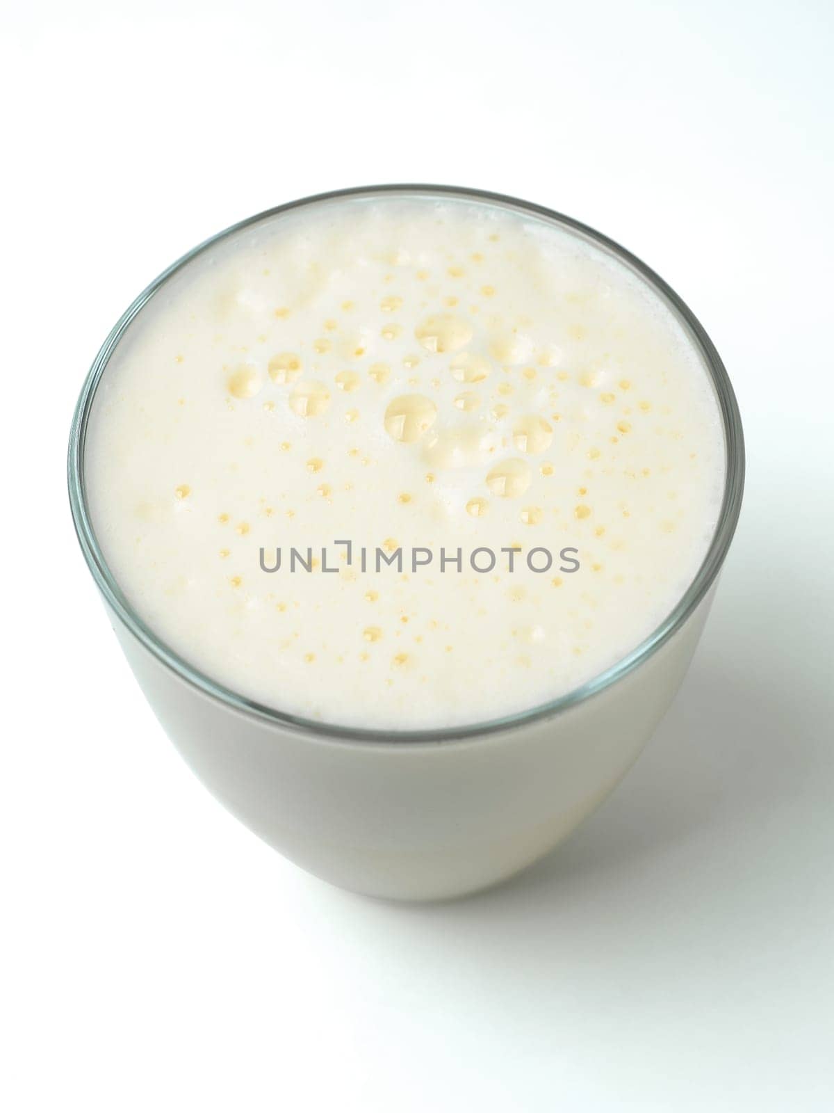 Vanilla milkshake with foam isolated on white. Delicious milk dessert with vanilla in glass isolated on white with clipping path.