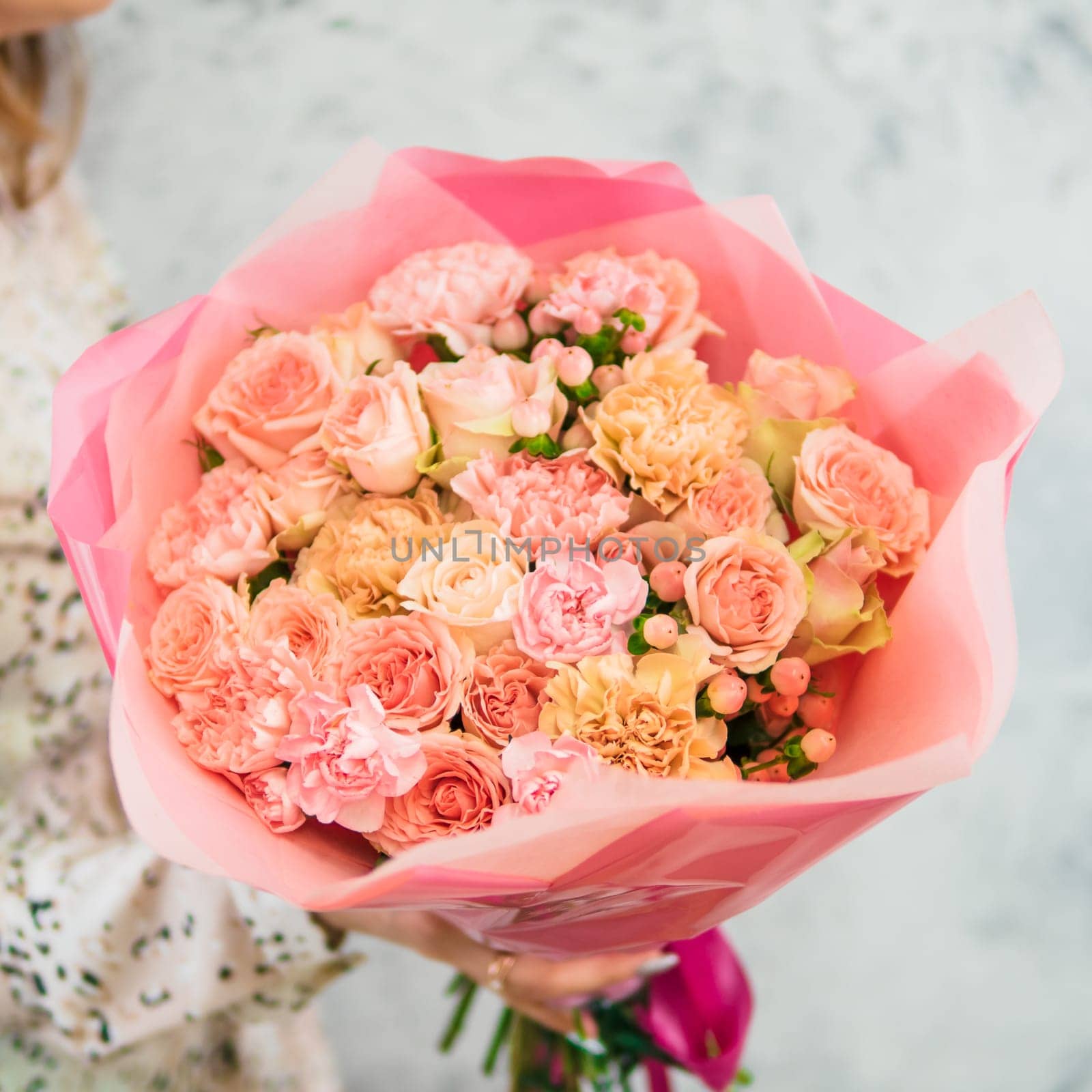 Beautiful bouquet with differen tpink flowers in woman hands. Nice subtle delicate pink bouquet with roses, dianthus, hypericum, clove. Shallow DOF