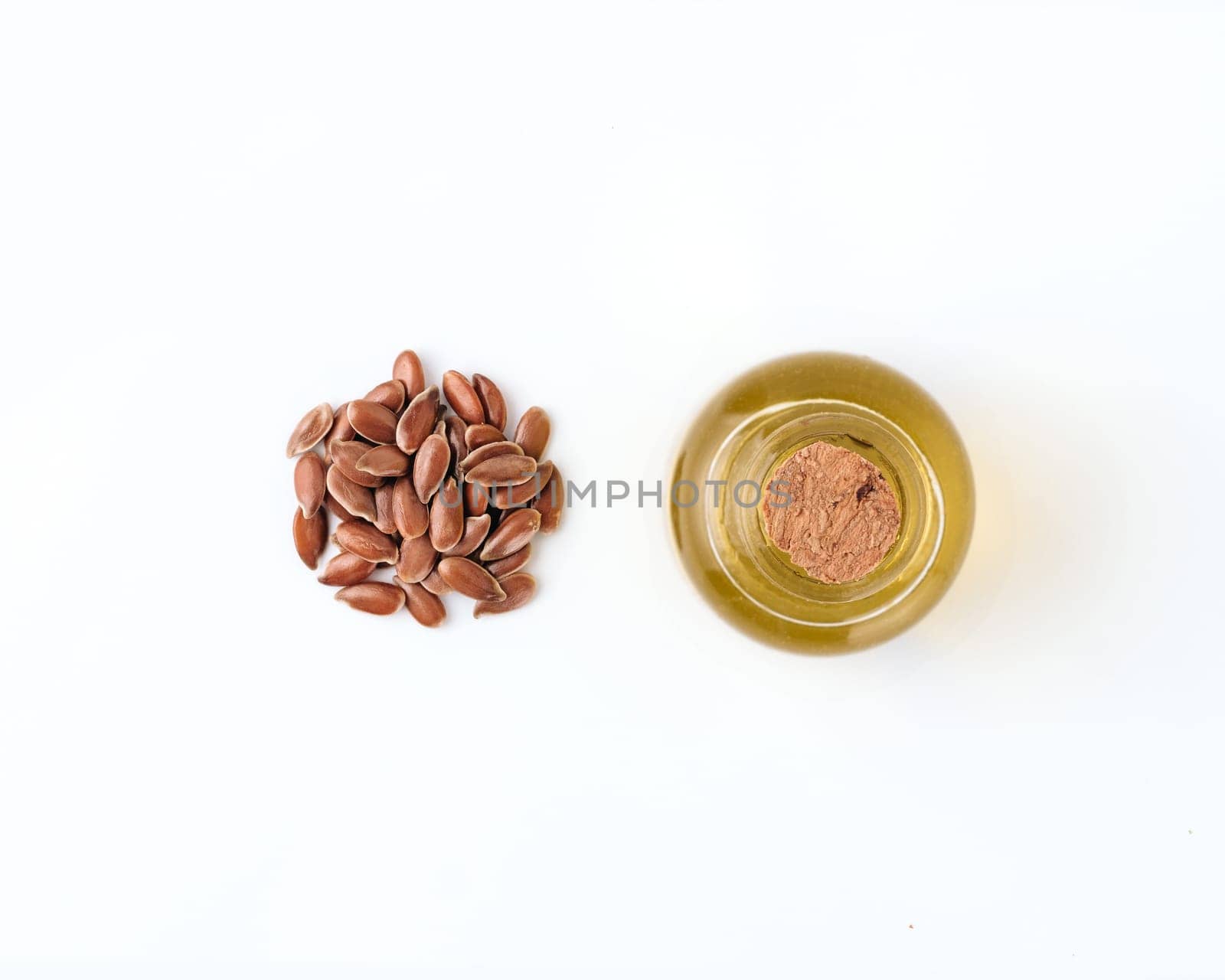 Linen seeds and linen raw oil isolated on white background. Heap of flax seeds and raw flax seed oil in small glass bottle isolated on white with clipping path, top view or flat lay. Macro