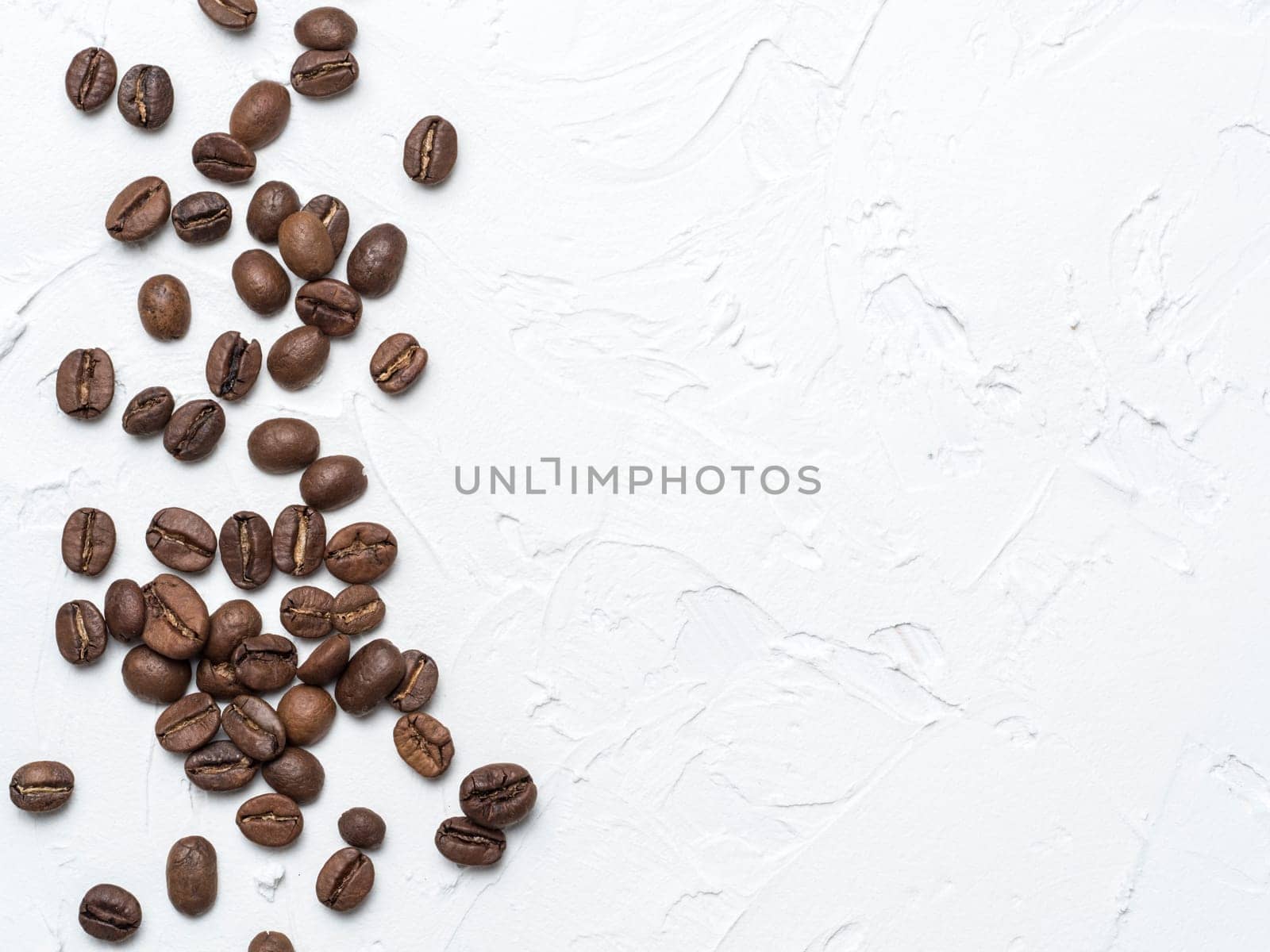 Coffee beans with copy space. Brown coffee beans on white concrete textured background. Top view or flat lay. Copy space.