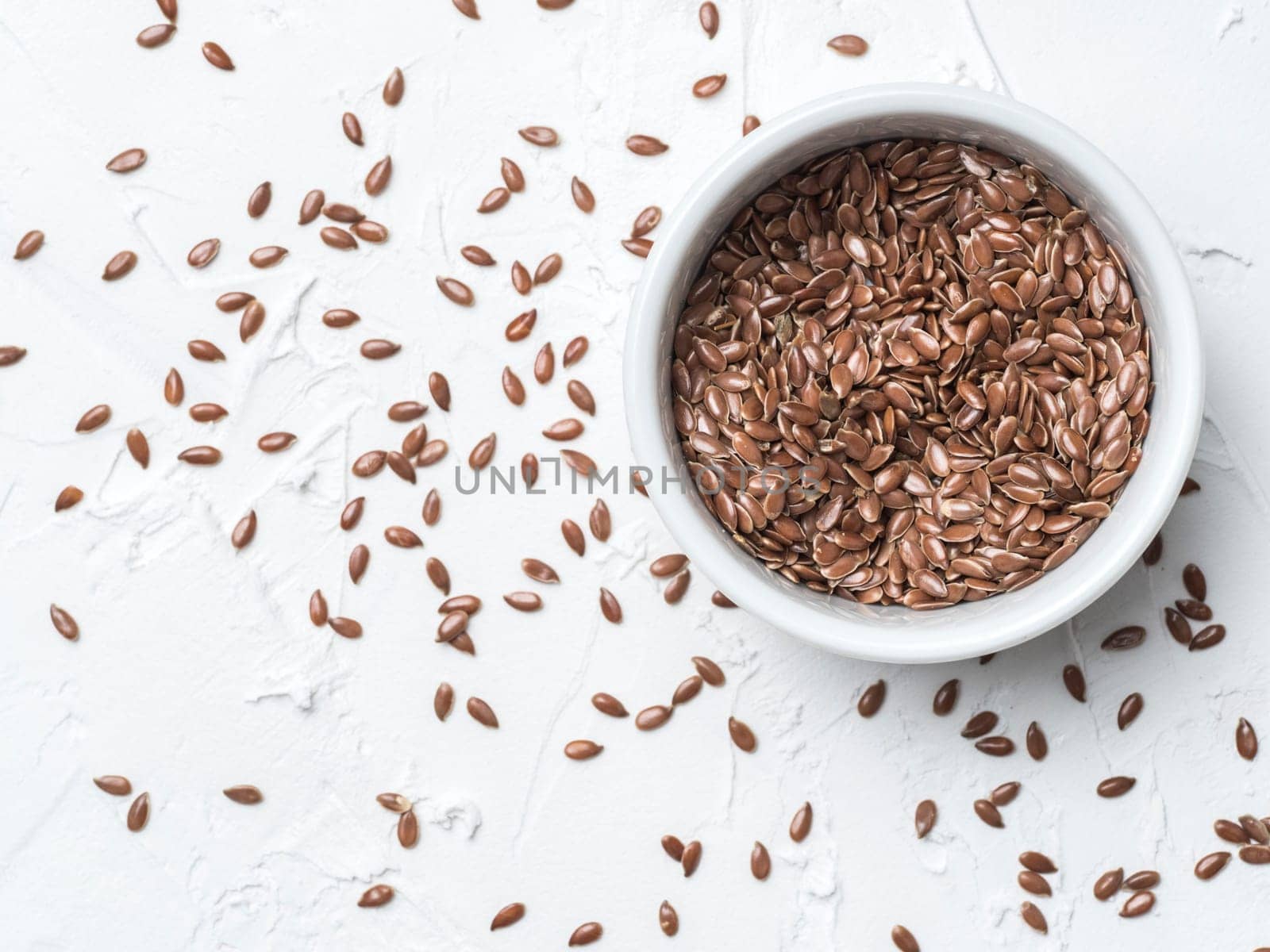 Flax seeds with copy space. Brown flax seed on white concrete textured background. Top view or flat lay. Copy space. Healthy food and diet concept