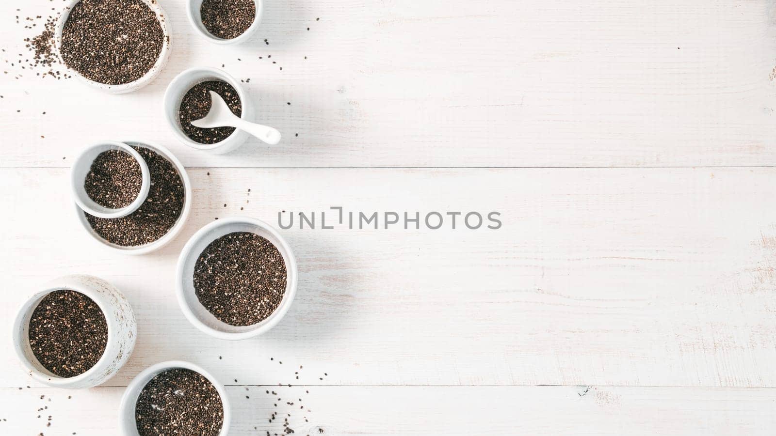 Organic chia seeds on white wooden table. Set of small bowls with organic chia seed. Superfood concept. Copy space. Top view or flat-lay. Banner