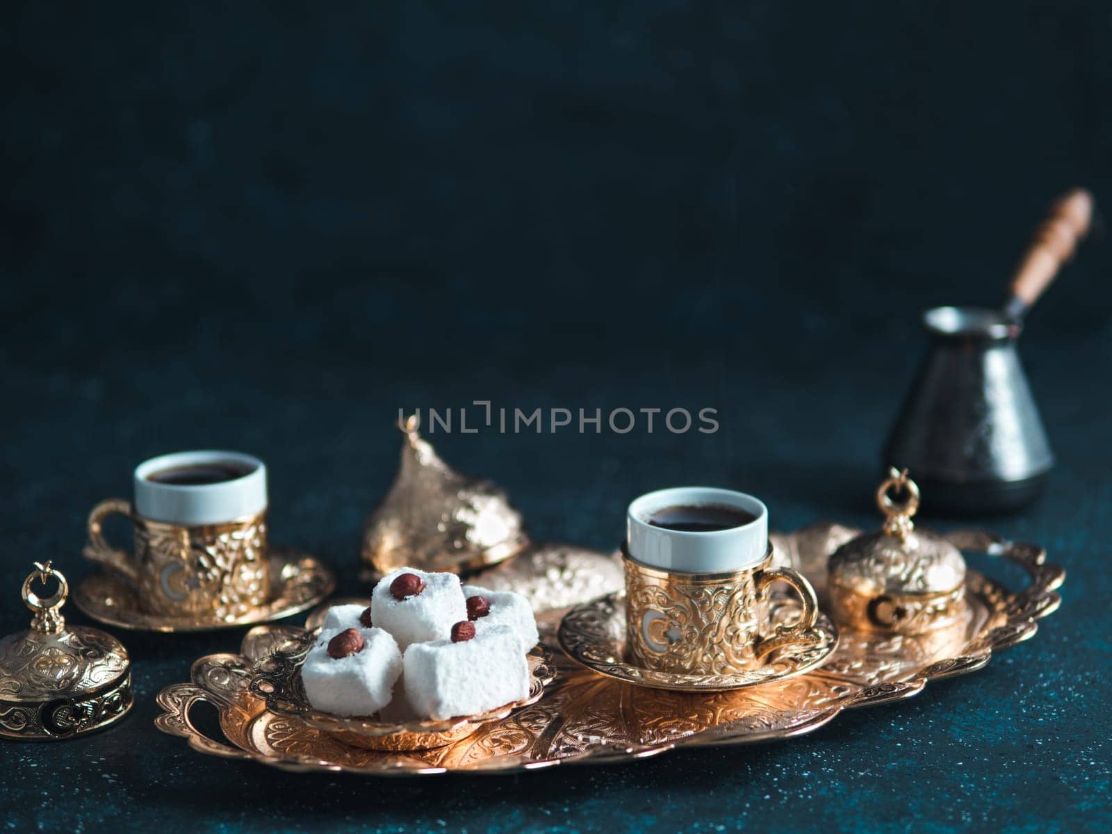 Turkish coffee with delight and traditional copper serving set on dark background. Assorted traditional turkish dilight or lokum and turkish coffee in metal traditional cups.Copy space.Selective focus