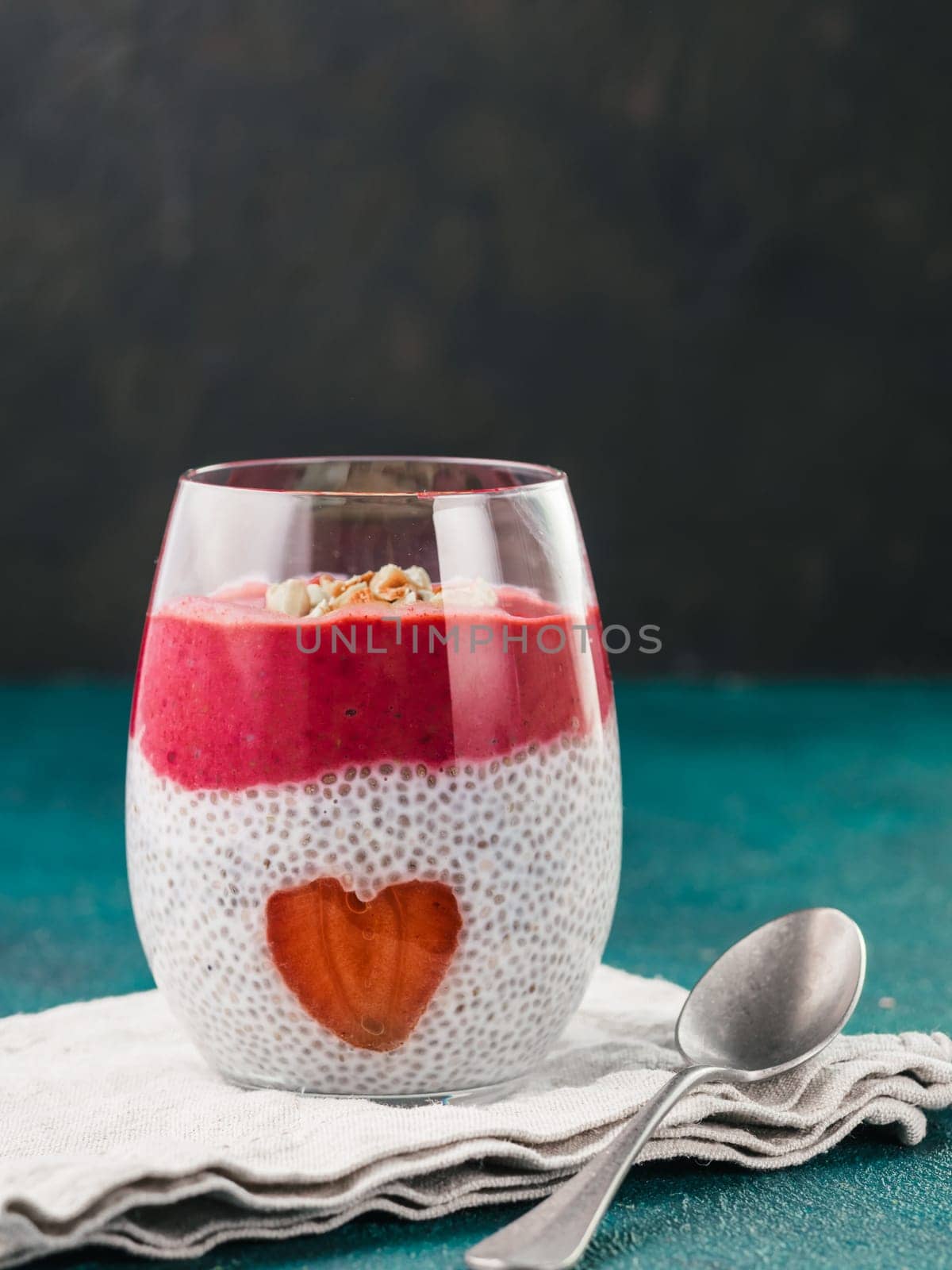Idea for healthy breakfast on Valentine's Day: Chia pudding with red berry puree, chopped almonds on top and strawberry in the shape of heart. Copy space for text