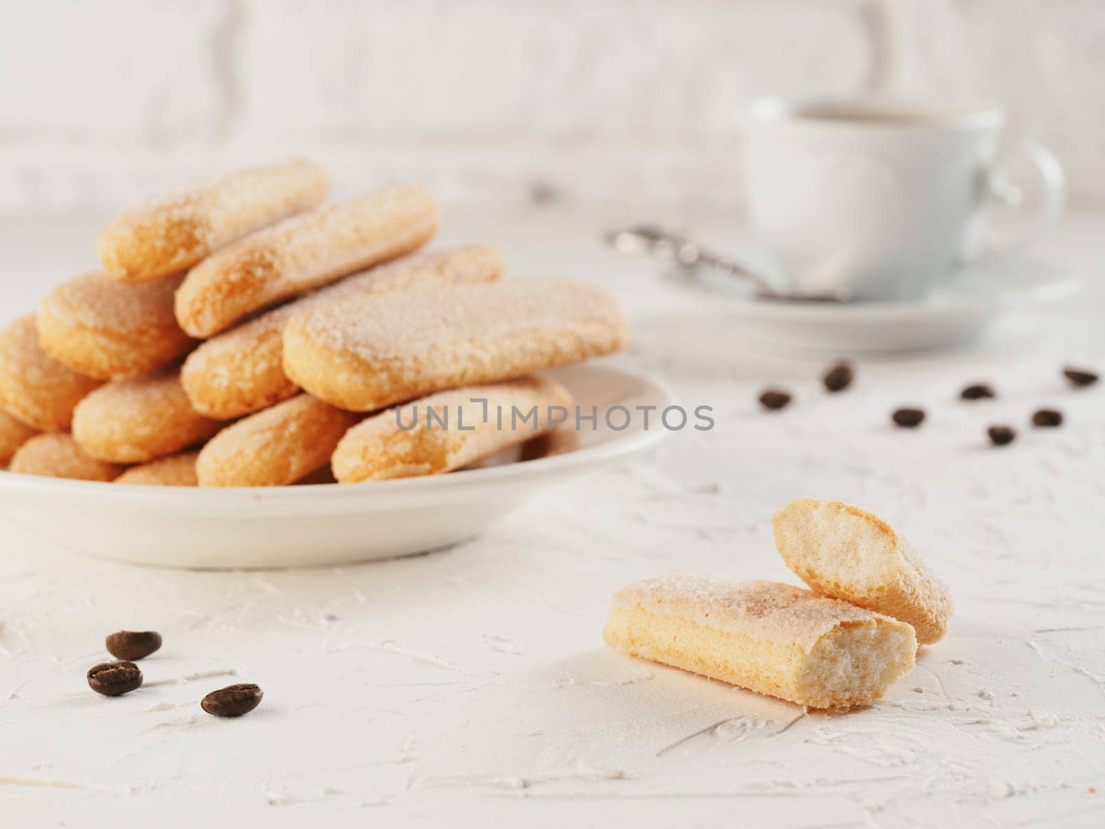 Italian cookie savoiardi and cup of coffee. Close up view of ladyfinger biscuit cookie on white concrete background. Copy space.