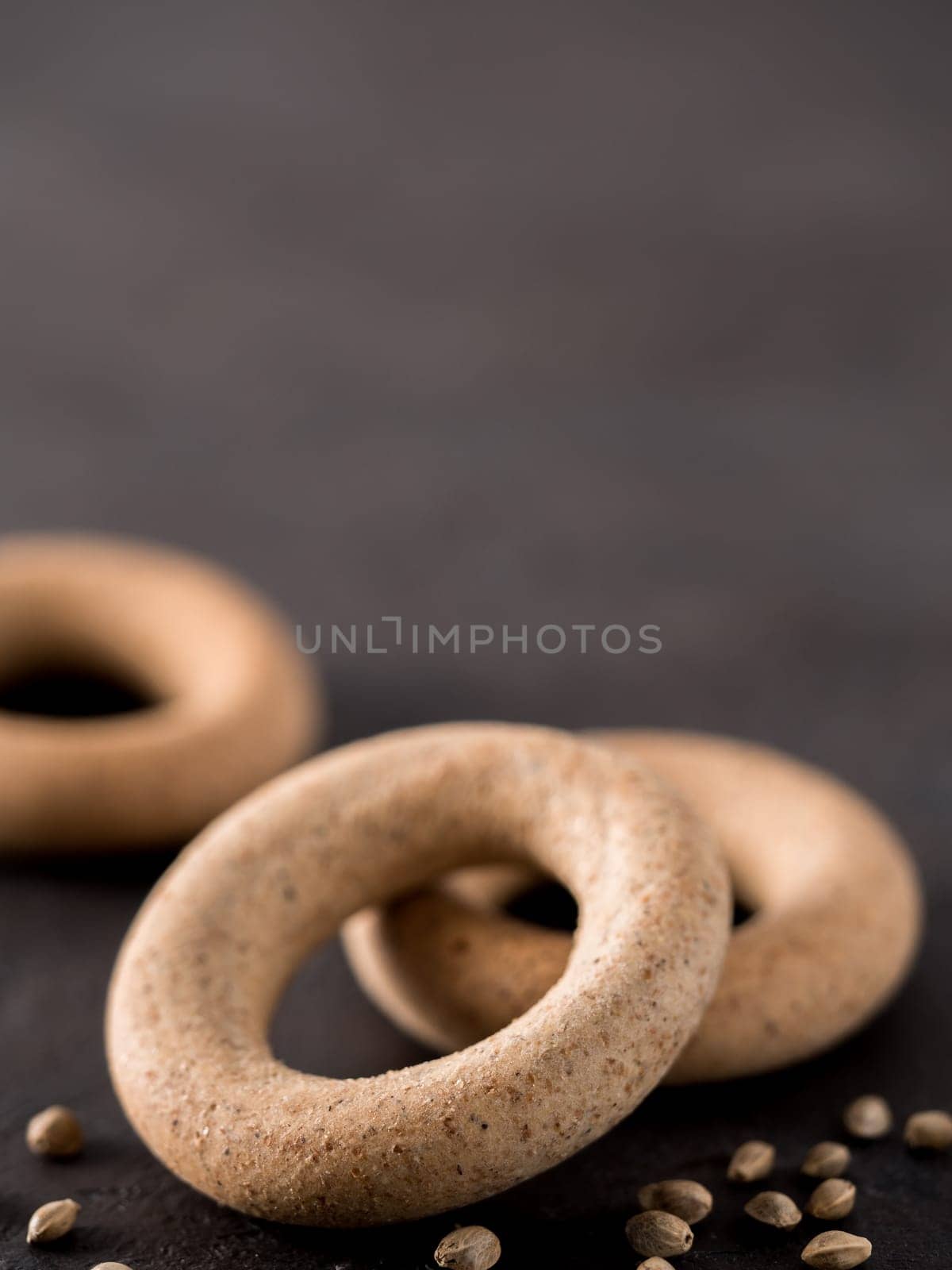 Ring-shaped cracknel with whole grain hemp seed flour and hemp seeds on black background. ring-shaped cracknel close up. Copy space Vertical.