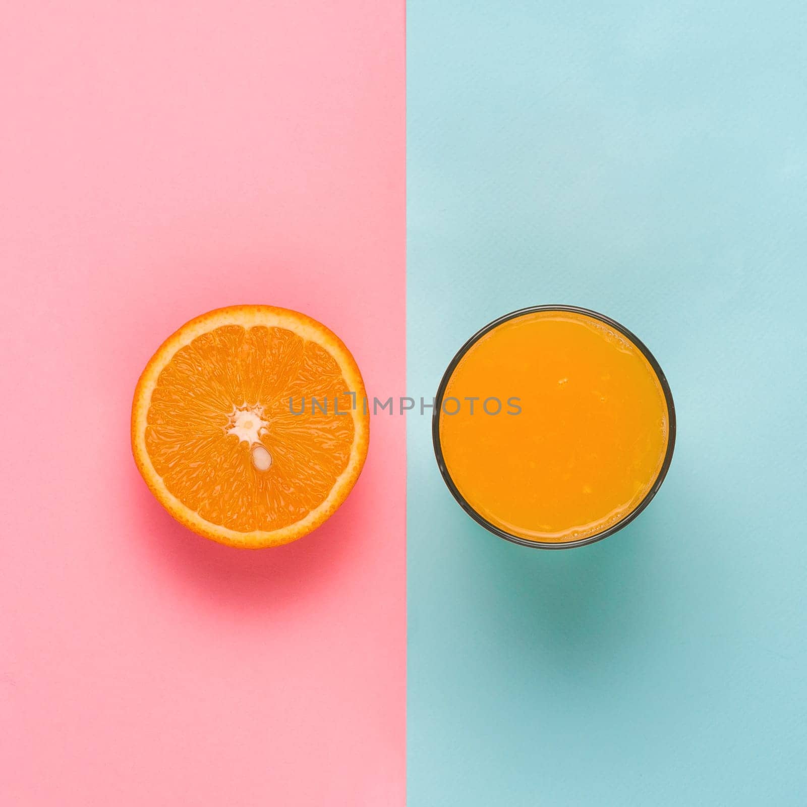 Glass of orange juice and half of orange on colorful background from above. Creative concept. Copy space. Top view