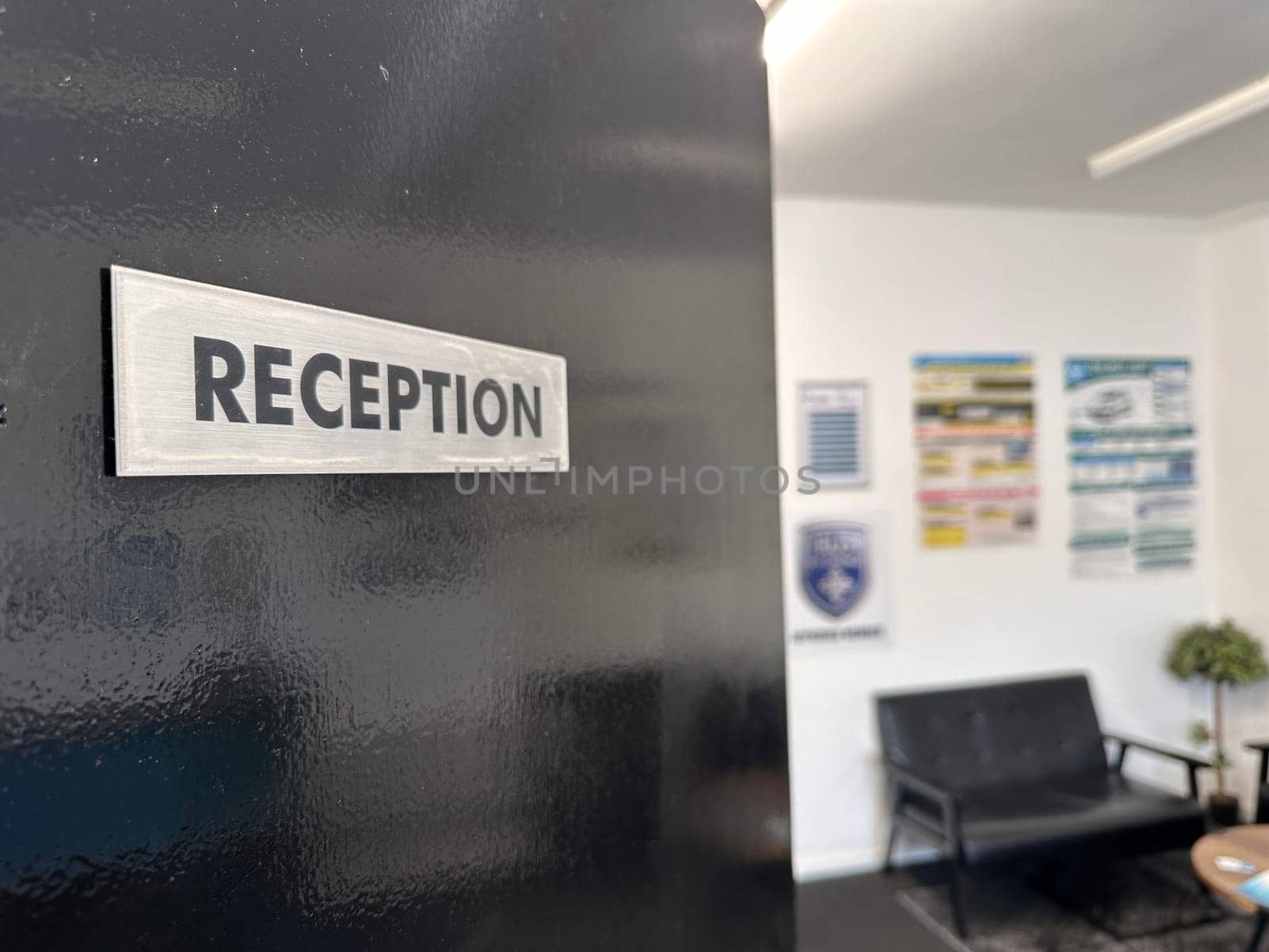 Reception sign on a black door, waiting area with couch on background