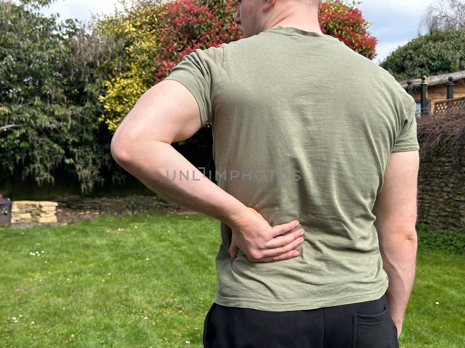 Cropped rear view shot of a man rubbing his lower back, having back pain