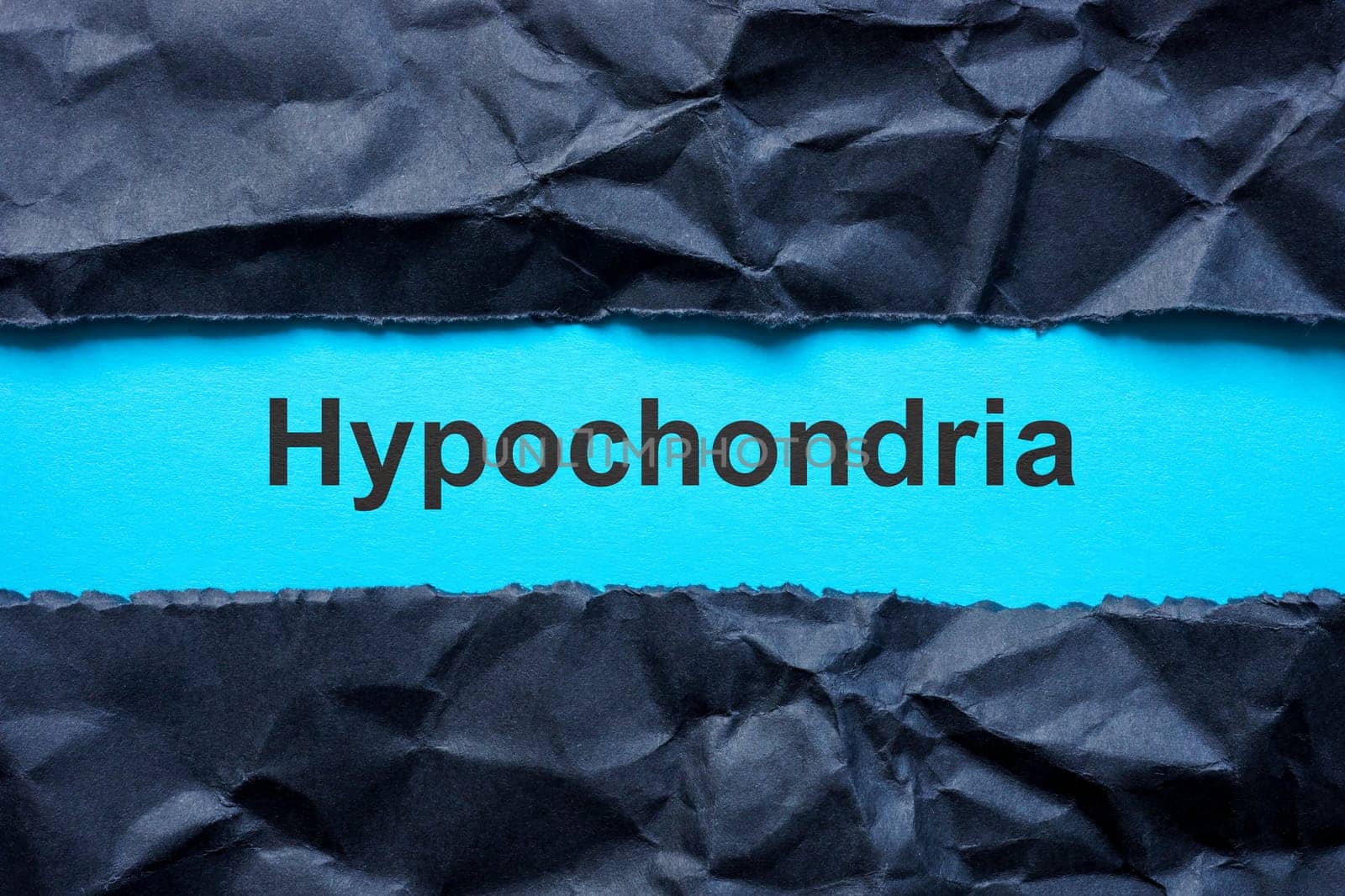 Torn black paper and word hypochondria on the blue surface.