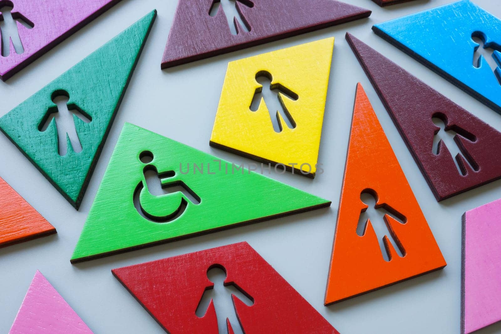 Multi-colored figures and one with a Disabled person sign as a concept of inclusivity and diversity. by designer491