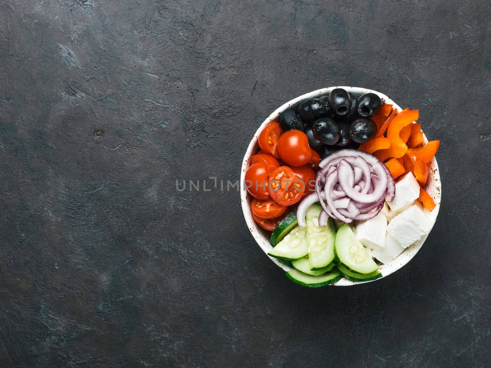 Greek Salad Bowl on dark black background, copy space. Above view of Bowl Greek Salad. Trendy food. Idea, recept and concept of modern healthy food.