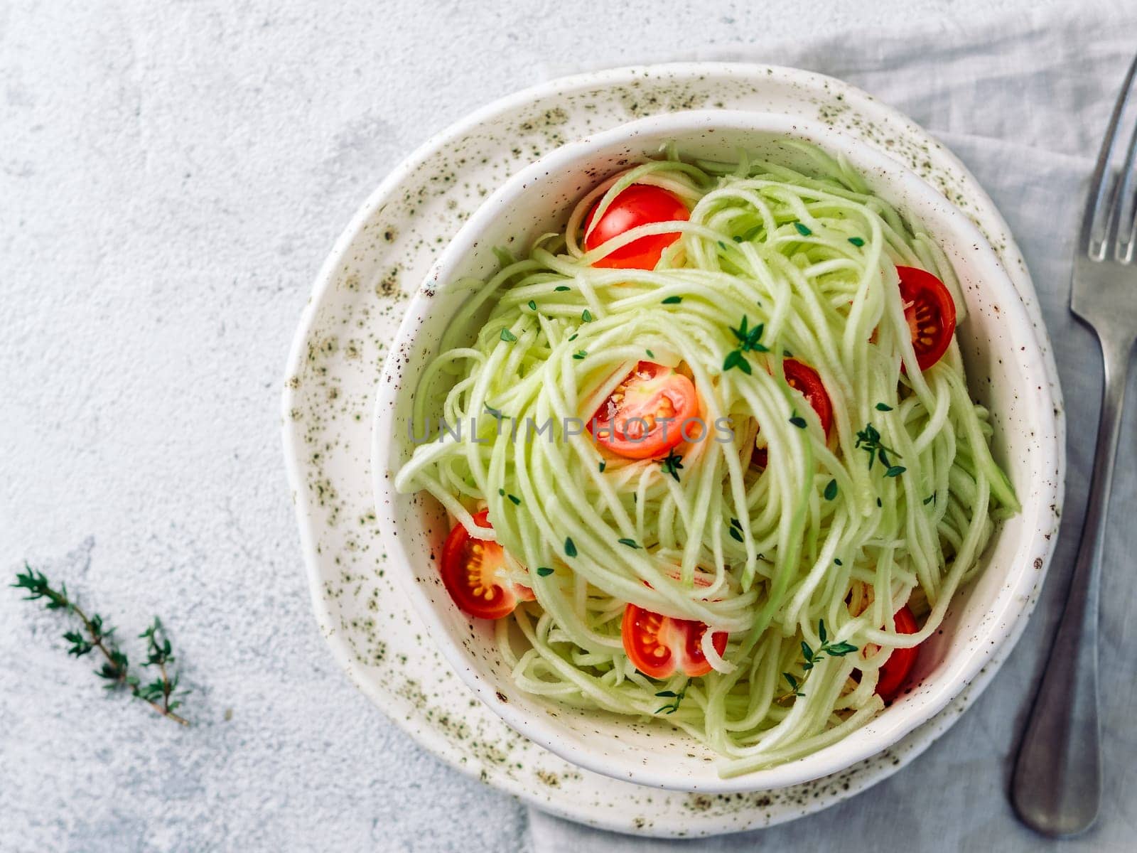 Zucchini noodles salad with cherry tomatoes. Vegetable noodles - green zoodles or courgette spaghetti salad ready-to-eat. Clean eating, raw vegetarian food concept. Copy space. Top view or flat lay.