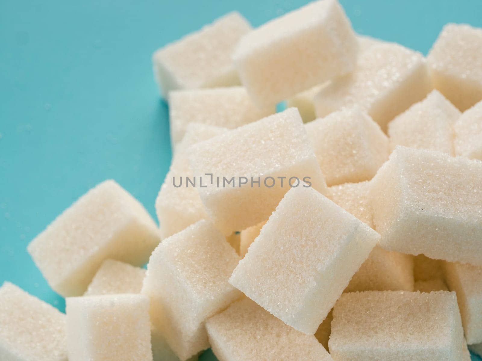 Background of sugar cubes. White cube sugar on blue background. White sugar close up