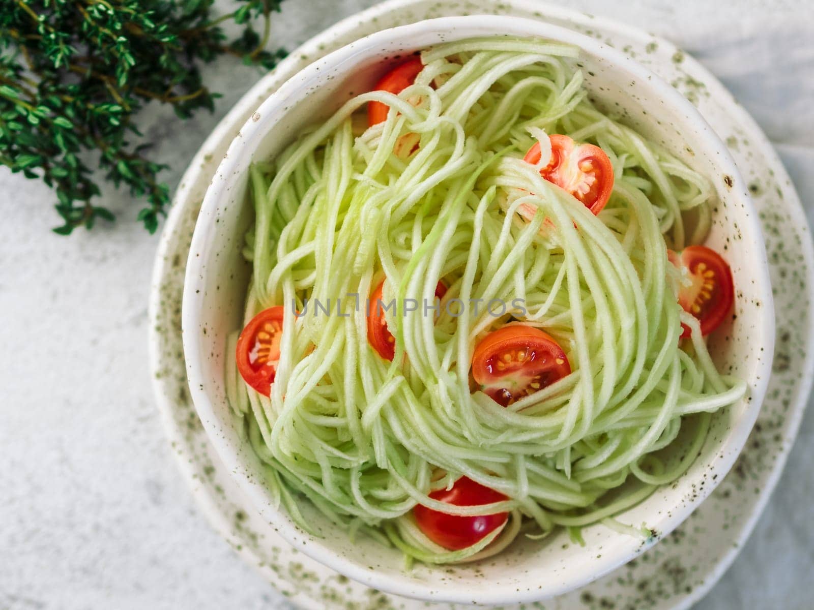 Zucchini noodles salad. Vegetable noodles - green zoodles or courgette spaghetti with cherry tomatoes in plate. Clean eating, raw vegetarian food concept. Copy space for text. Top view or flat lay