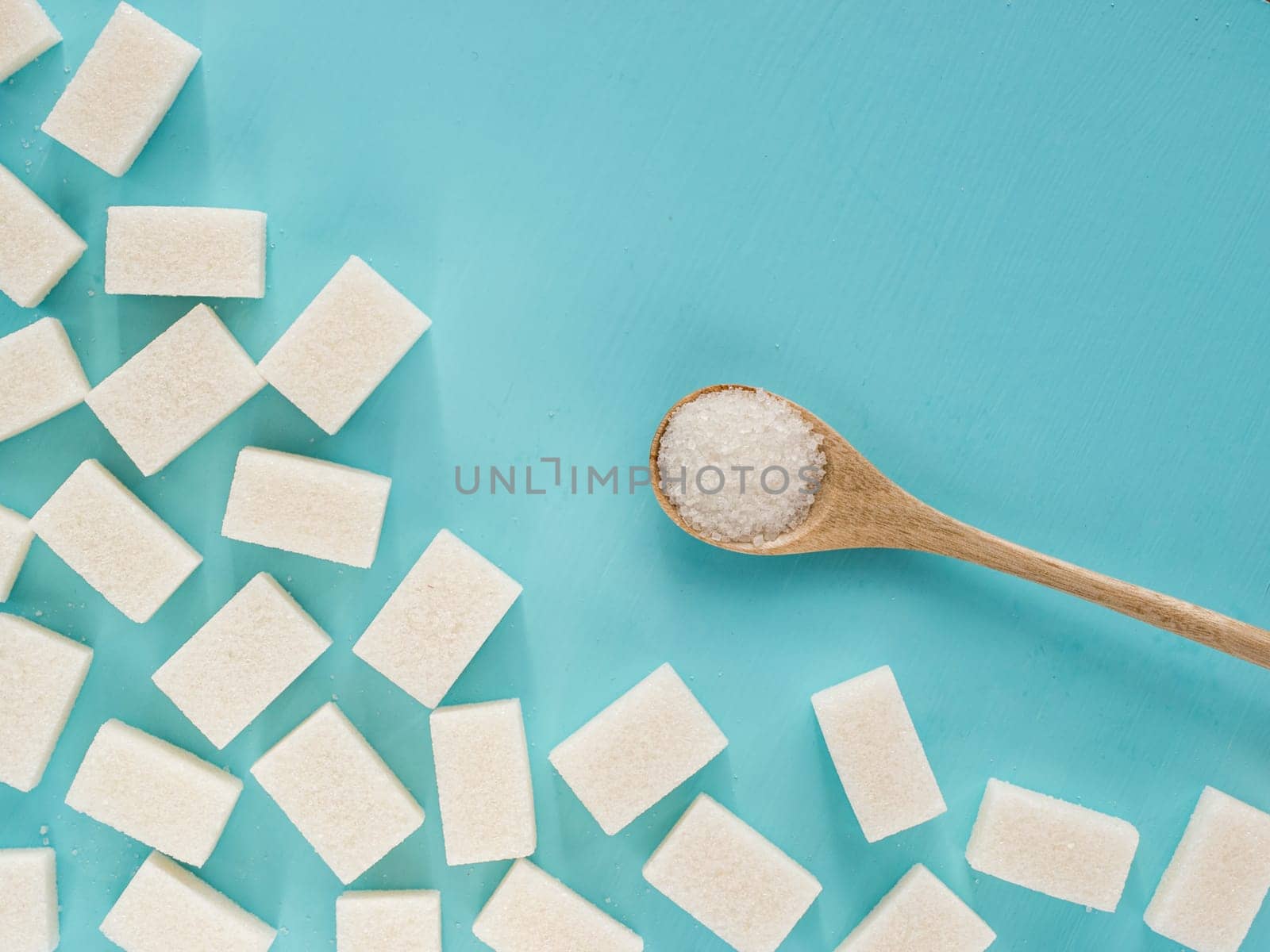 background of sugar cubes and sugar in spoon. White sugar on blue background. Sugar with copy space. Top view or flat lay