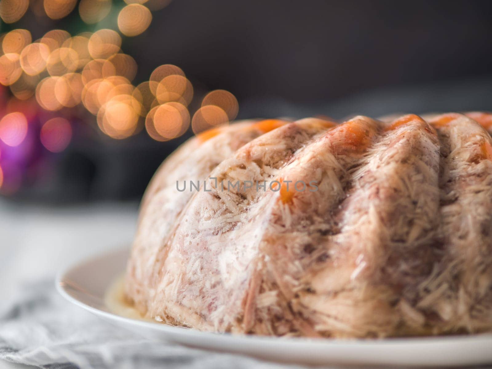 Homemade delicious jelly meat on festive Christmas table. Close up view of perfect jellied meat, aspic, galantine with carrot. Copy space for text.