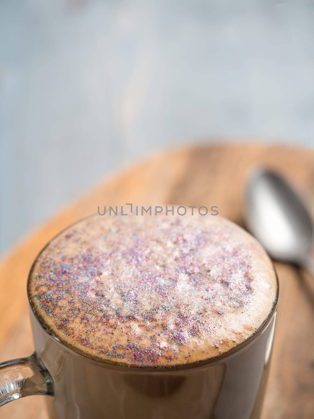 Trendy Coffee with edible glitter. Cup of sparkly coffee or diamond cappuccino on gray table. Copy space for text
