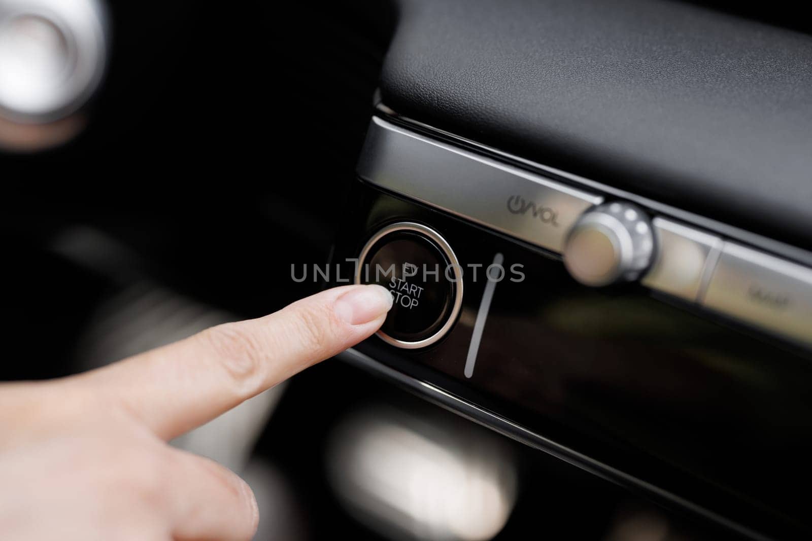 Pressing Stand By Power Button To Turn On and Off the Electric Car Close-Up. Push start stop button of ev car. Finger press the button to start the car engine. Concept of transportation and technology by uflypro