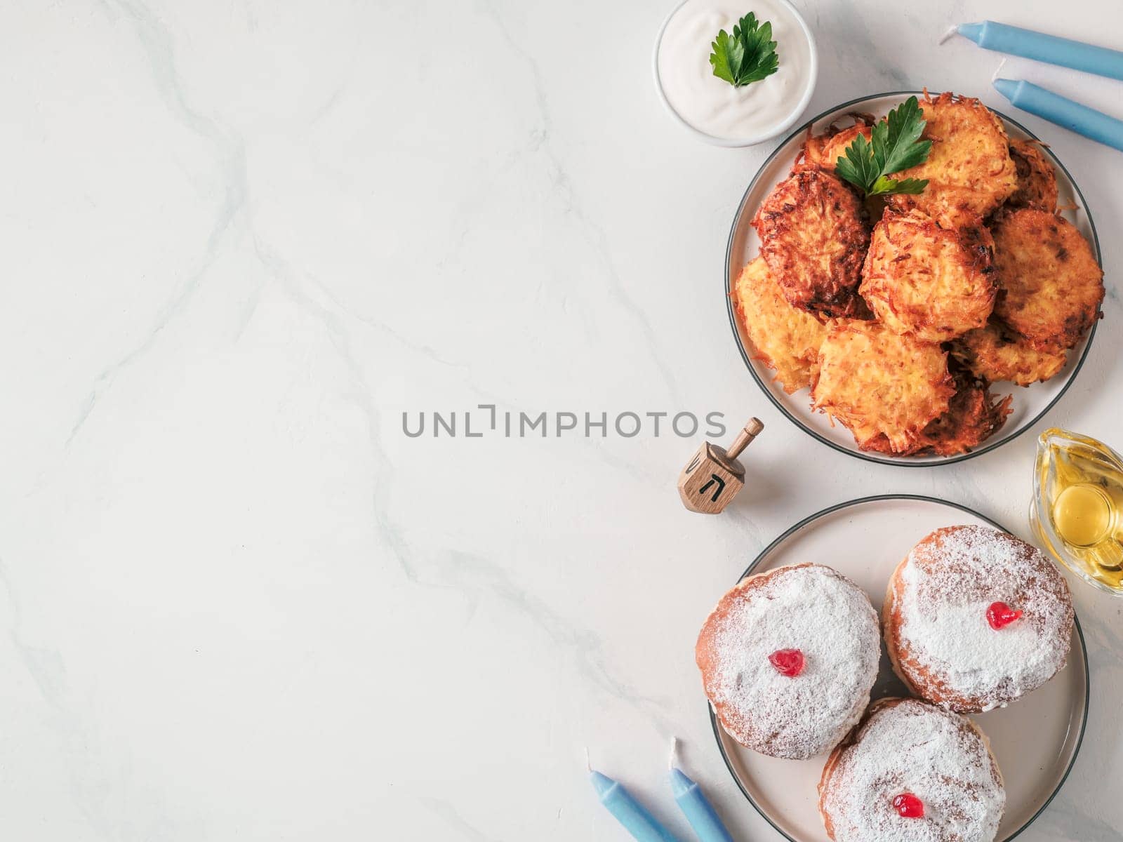 Jewish holiday Hanukkah concept and background. Hanukkah food, oil, candles and traditional spinnig dreidl. Top view or flat lay. Copy space for text.