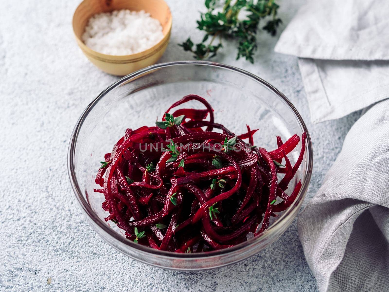 Raw beetroot noodles salad. Vegetable noodles - beet spaghetti in glass plate over gray cement background. Copy space for text. Ideas and recipe for Clean eating, raw vegetarian food concept.