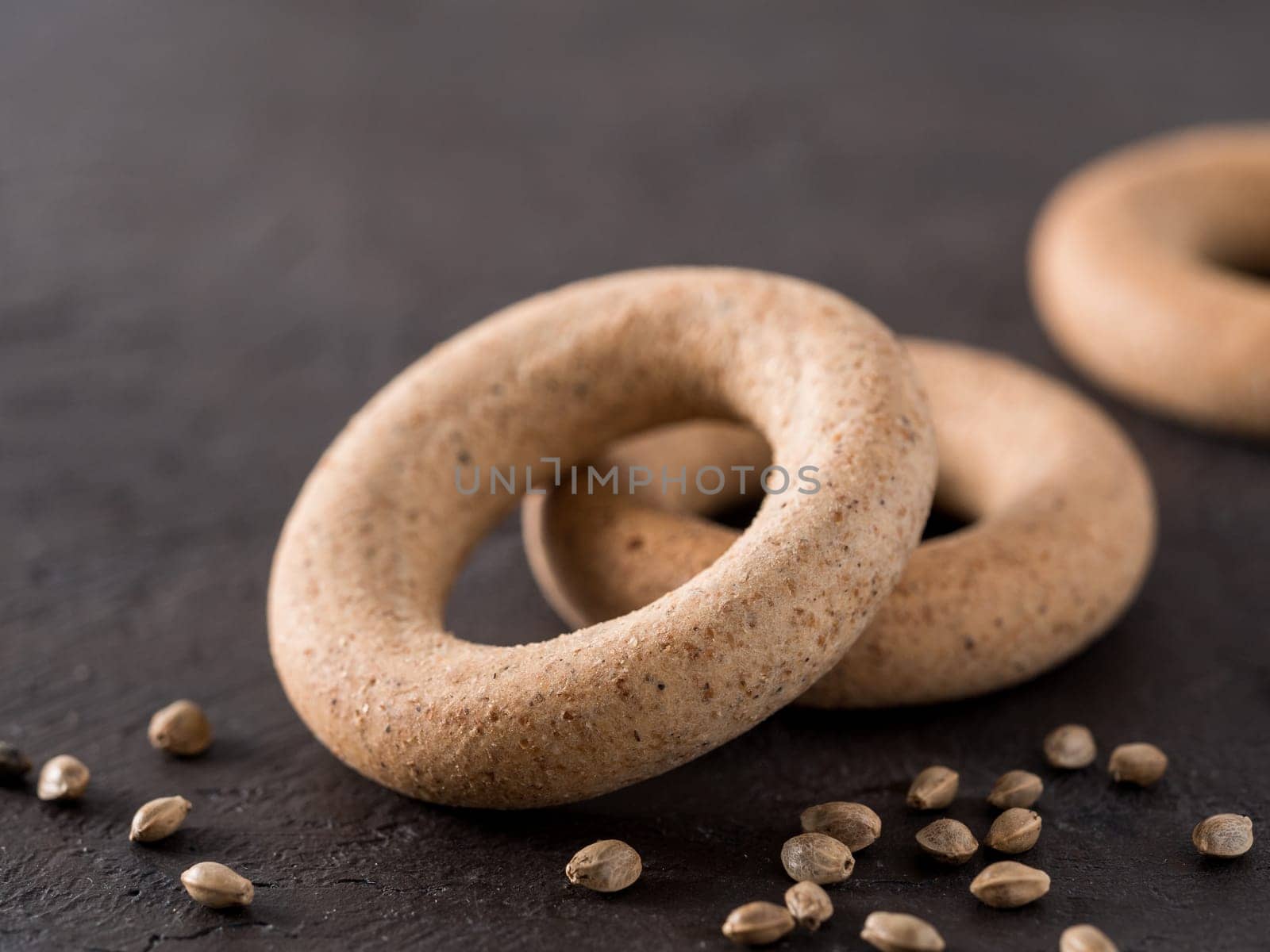 Ring-shaped cracknel with whole grain hemp seed flour and hemp seeds on black background. ring-shaped cracknel close up. Copy space