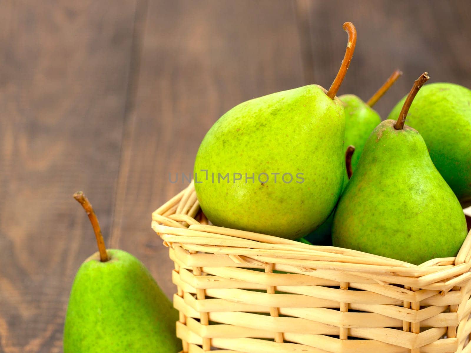 Healthy organic pears in basket on wooden table by fascinadora