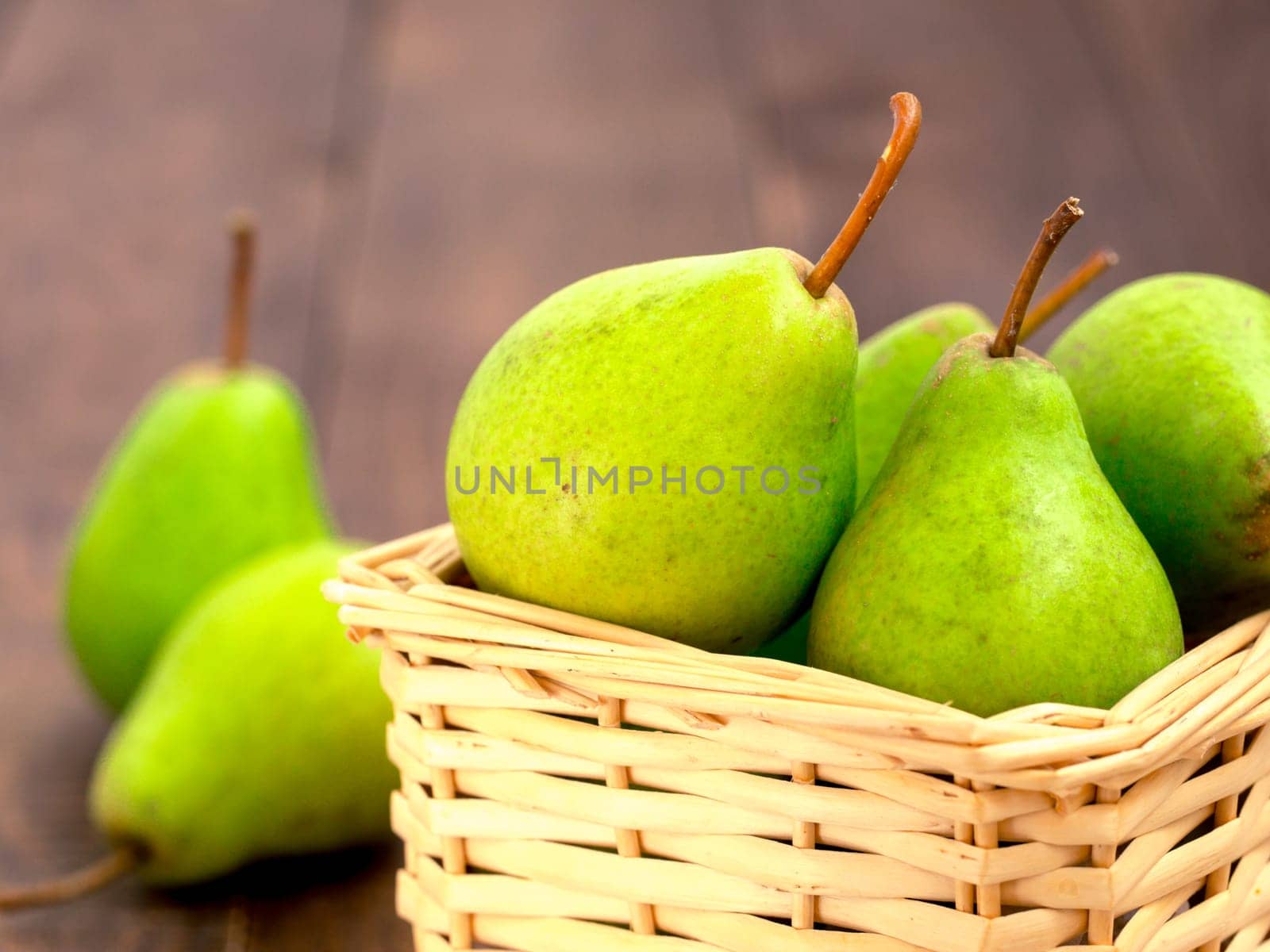 Healthy organic pears in basket on wooden table by fascinadora