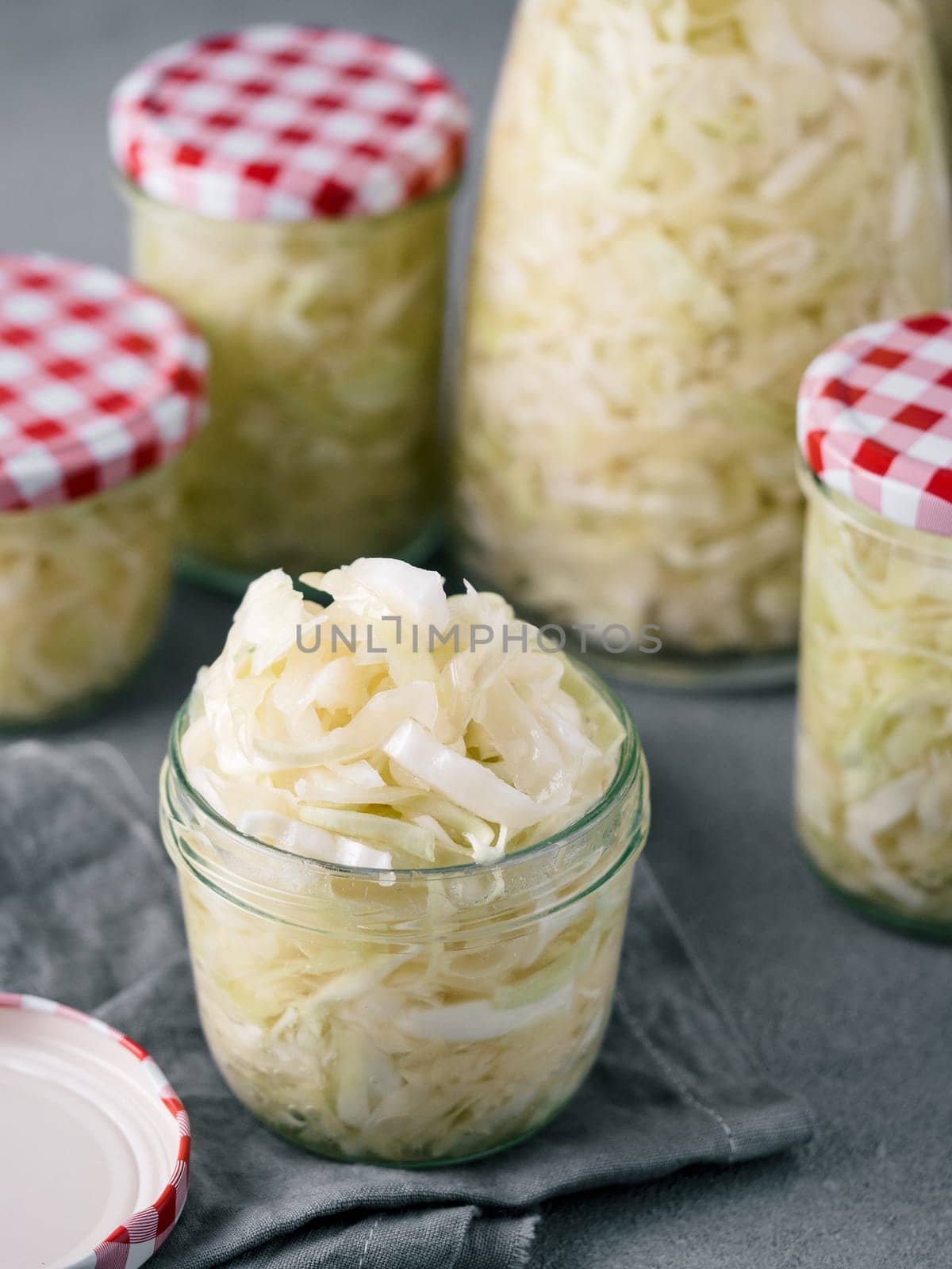 Sauerkraut in open glass mason jar. Pickling cabbage at home on table. The best natural probiotic. Homemade kraut., copy space for text. Vertical.