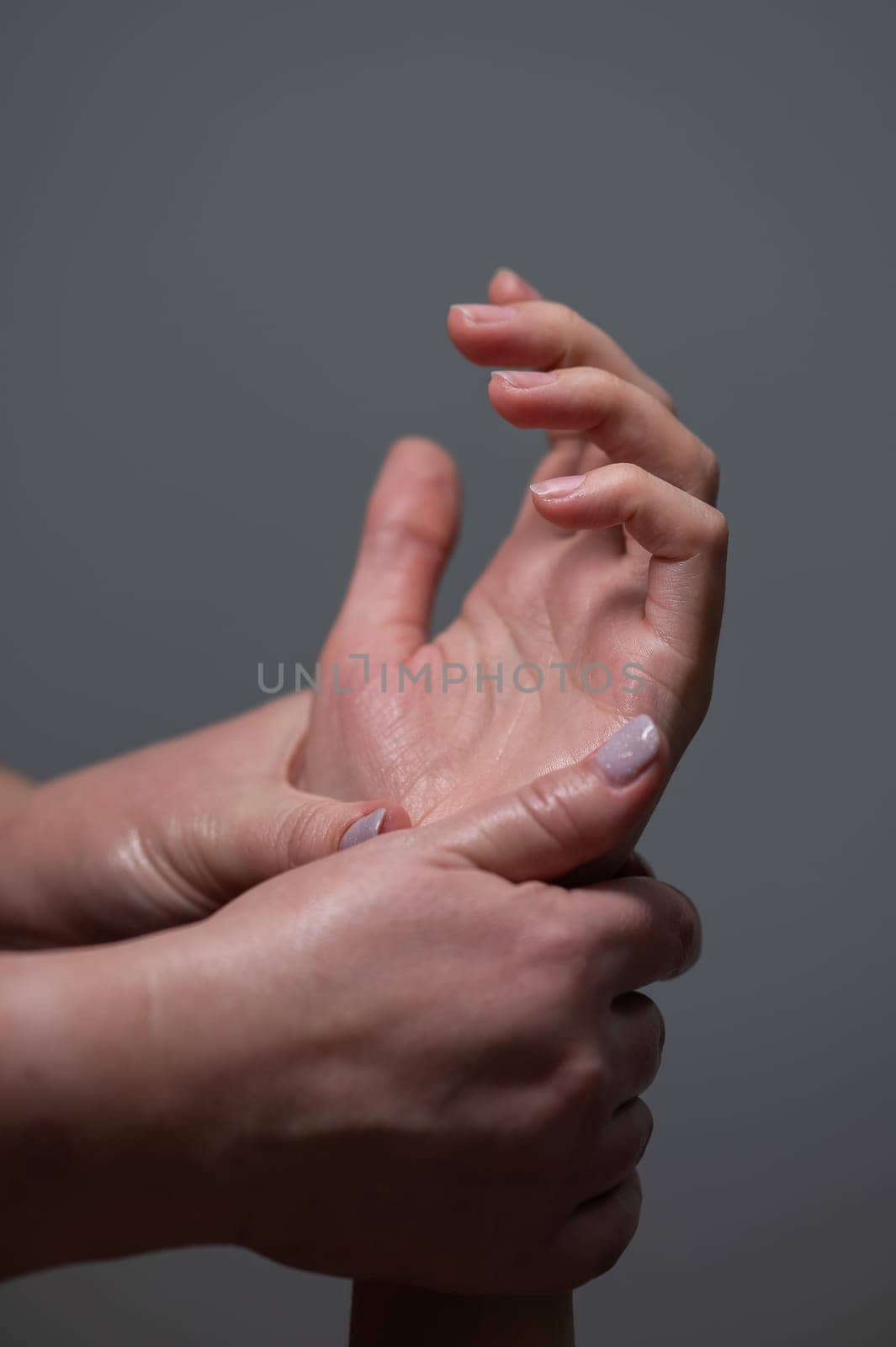 The masseuse massages the client's palms. Close-up of hands at a spa treatment. Vertical photo. by mrwed54