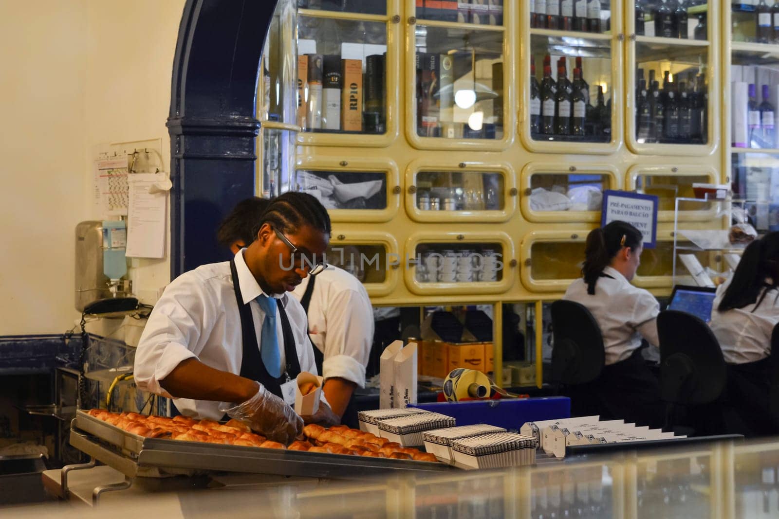 The worker fills the boxes Pasteis de Belem in the historical pastry store in Lisbon. by Godi