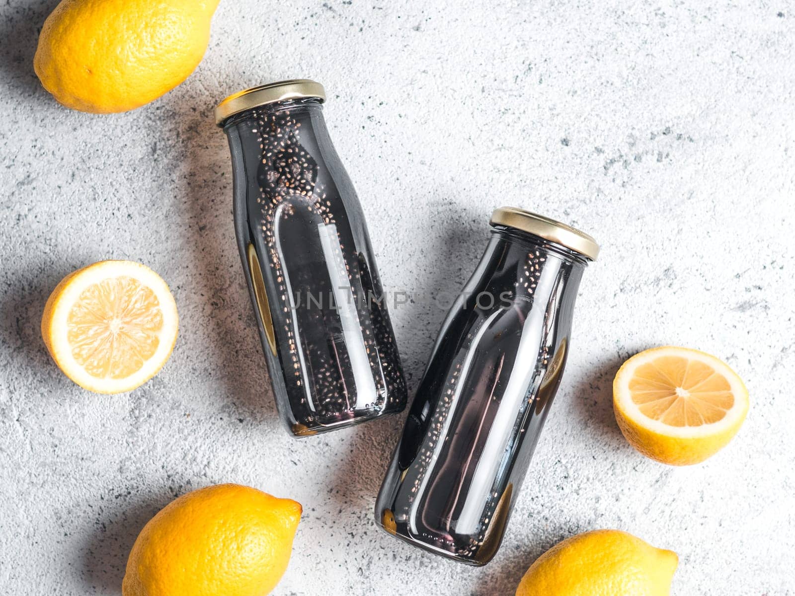 Detox activated charcoal black chia water or lemonade with lemon. Two bottle with black chia infused water. Detox drink idea and recipe. Vegan food and drink. Top view. Copy space for text.