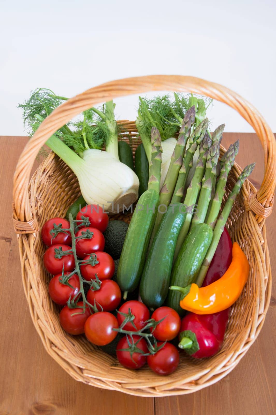 fresh assorted Vegetables in a basket on a wooden table, consumer vegetarian basket, tomatoes, fennel, paprika, asparagus,, cucumbers, avocado, Healthy eating concept, top view, High quality photo
