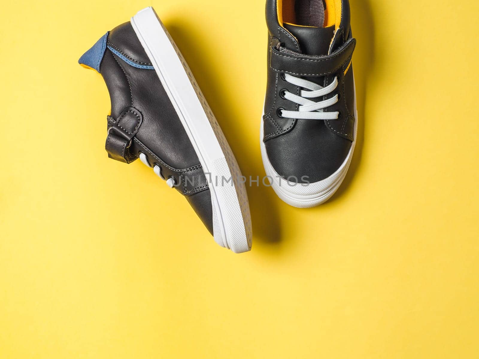 Gray and yellow sneakers on yellow background by fascinadora