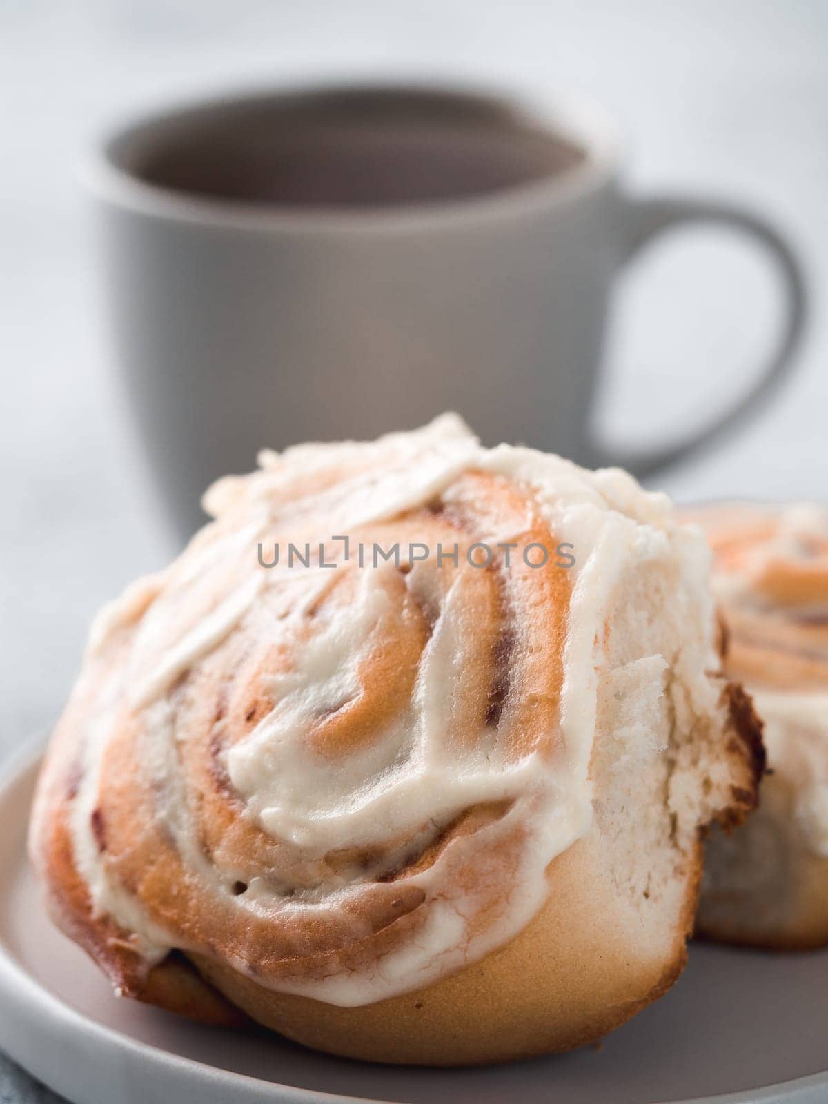 Vegan swedish cinnamon buns Kanelbullar with pumpkin spice,topping vegan cream cheese in plate with tea cup on table. Idea and recipe pastries - perfect cinnamon rolls.Copy space.Shallow DOF. Vertical