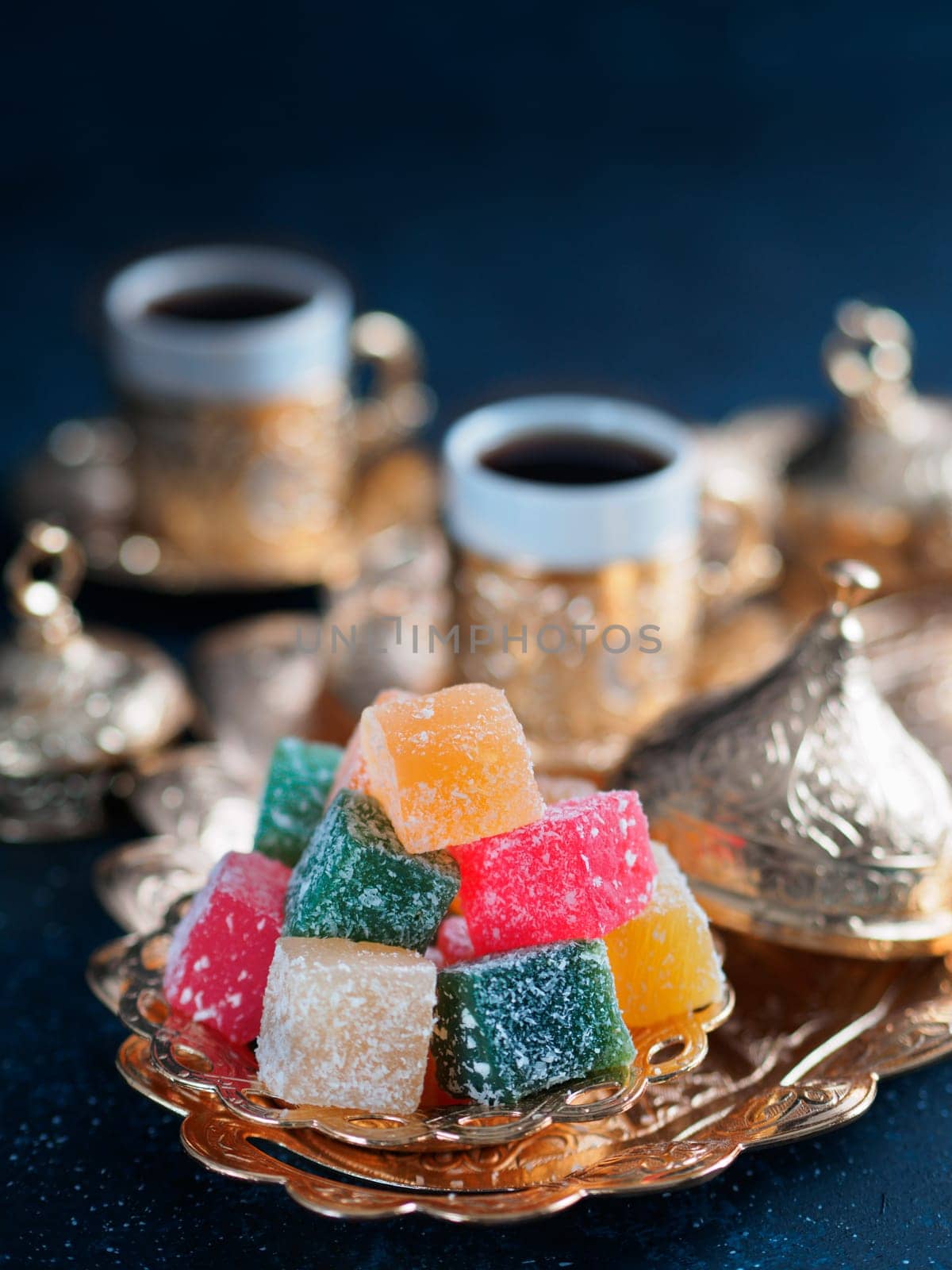 Turkish coffee with delight and traditional copper serving set on dark background. Assorted traditional turkish dilight or lokum and turkish coffee in metal traditional cups.Copy space.Selective focus