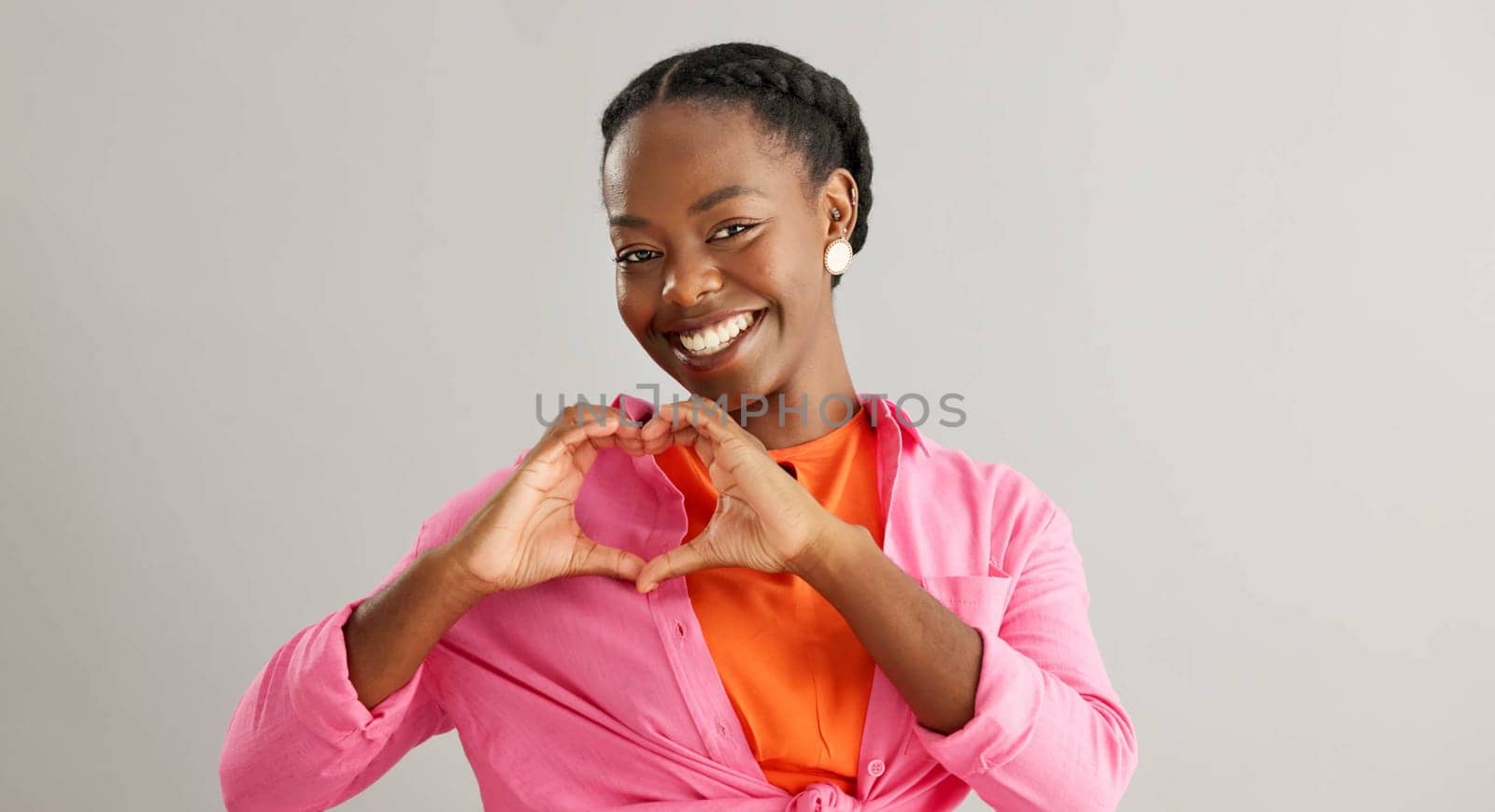 Happy, black woman and heart hands with love for care, support or romance on a gray studio background. Portrait of African female person with smile, like emoji or shape for romantic gesture on mockup.