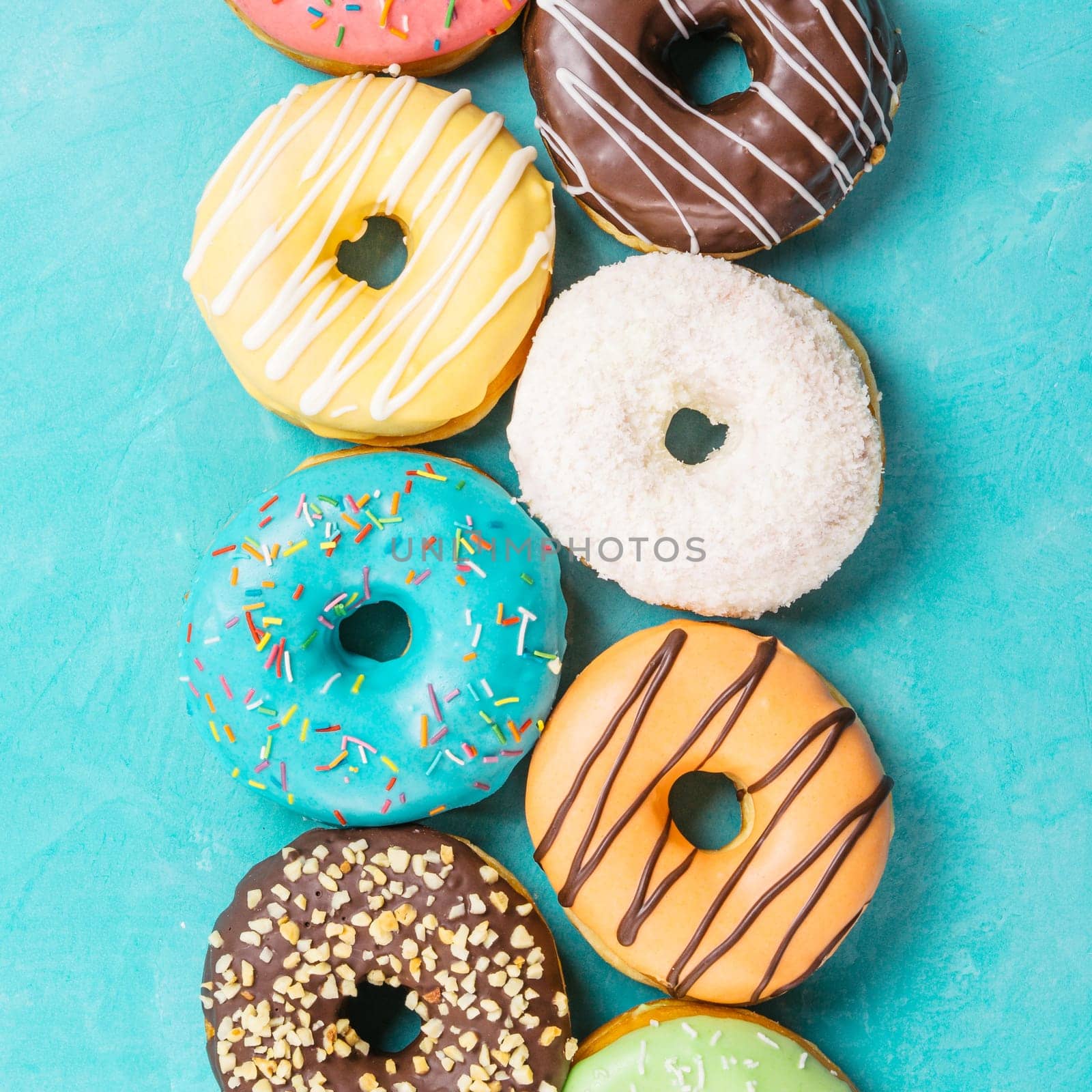 Top view of assorted donuts on blue concrete background. Colorful donuts background. Various glazed doughnuts with sprinkles.