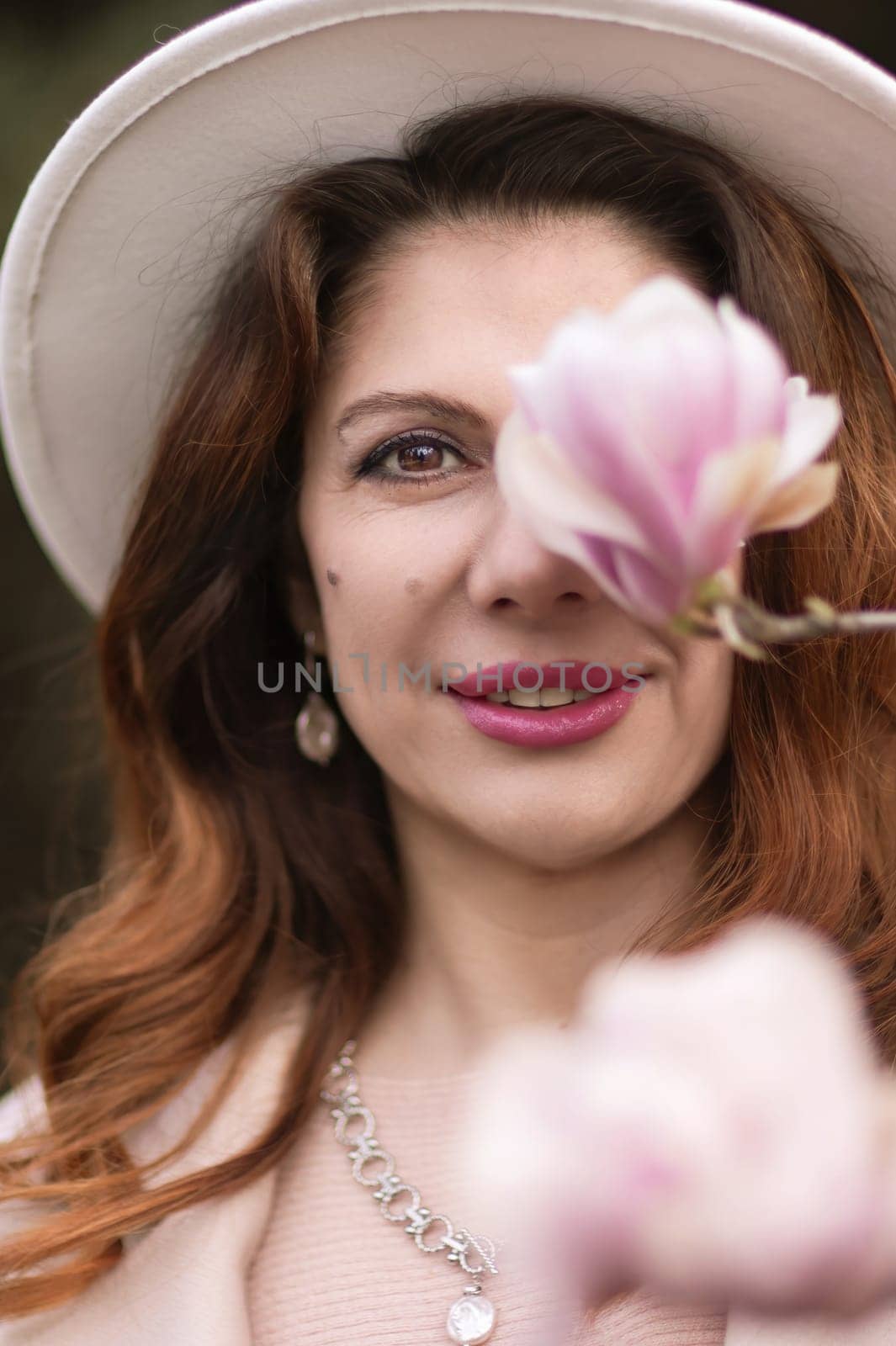 Woman holds magnolia flowers, surrounded by blossoming trees. Captured during spring, showcasing natural beauty and seasonal change