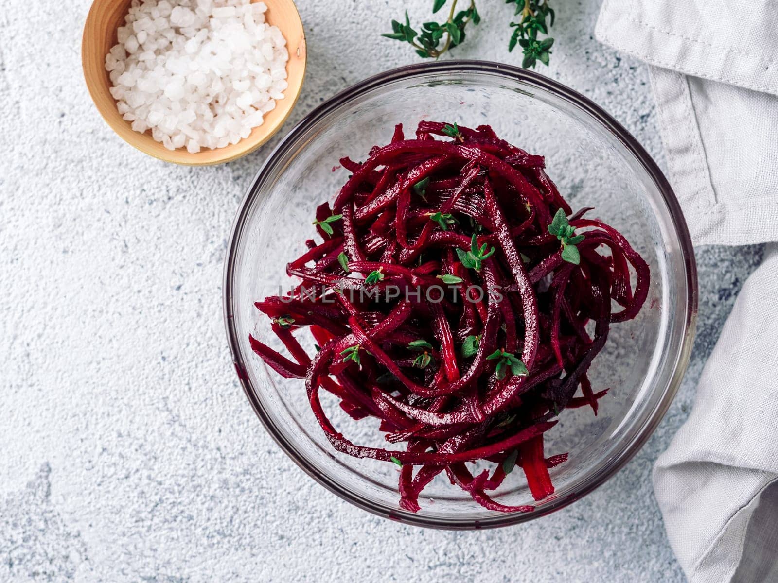 Raw beetroot noodles salad. Vegetable noodles - beet spaghetti on gray cement background. Copy space for text. Ideas and recipe for Clean eating, raw vegetarian food concept. Top view or flat lay.