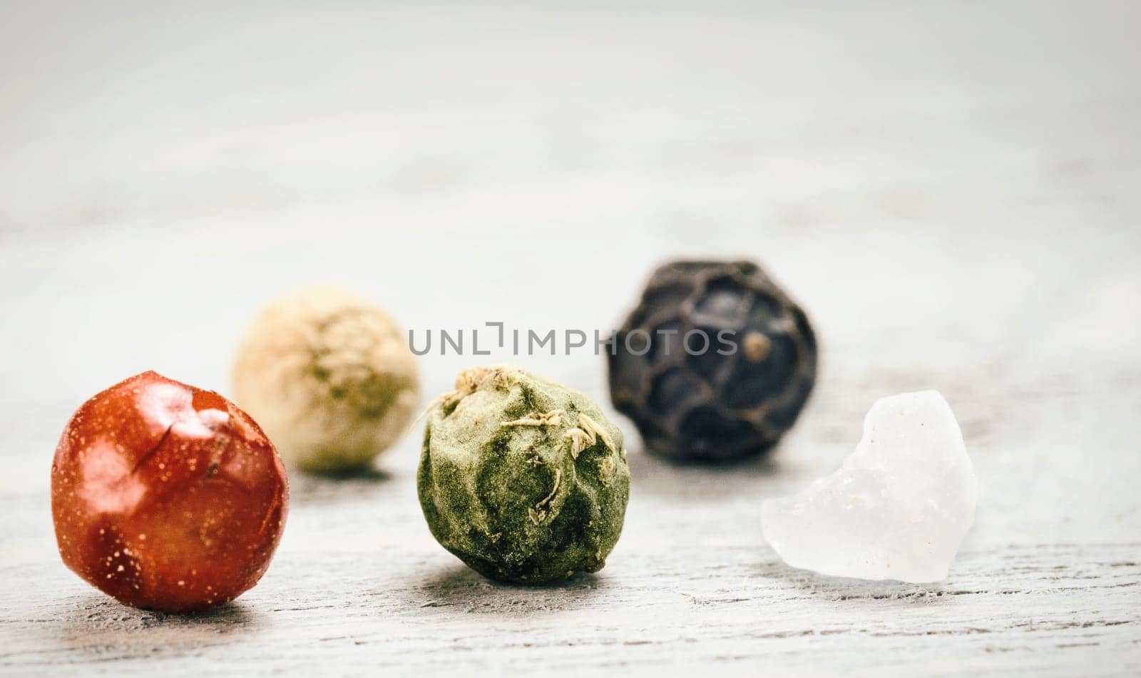 Extreme close-up view of peppercorns and salt on gray wooden table. Various colorful pepper grains with copy space. Cooking concept.