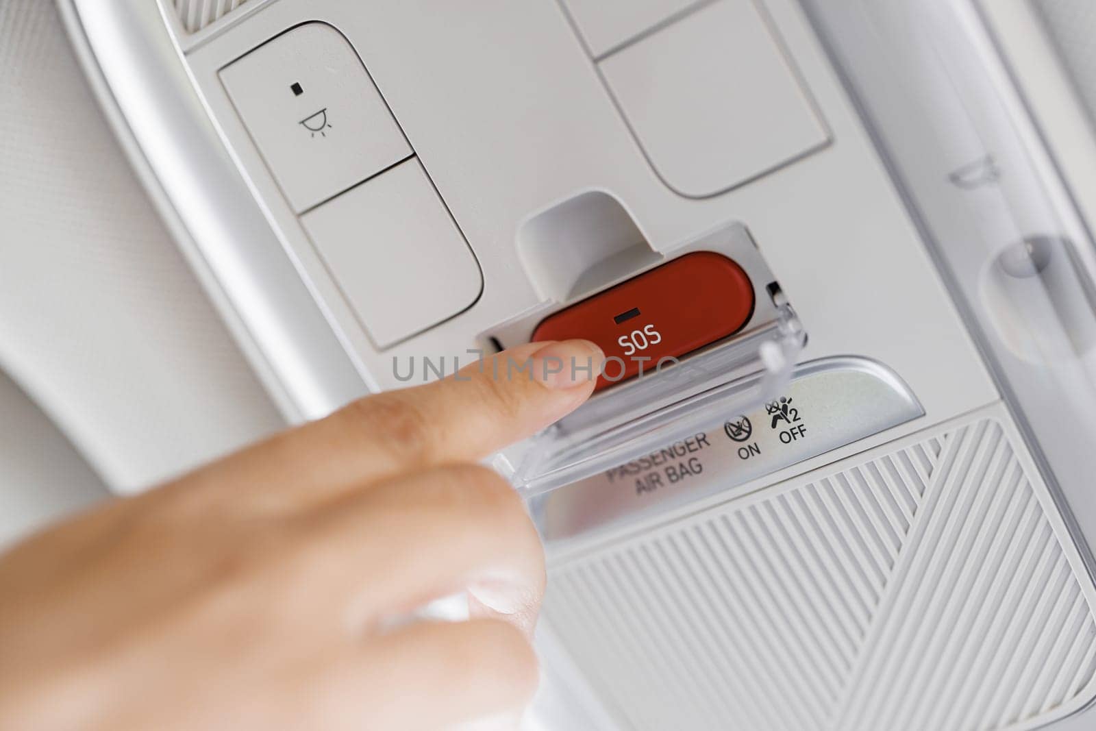 Woman with his finger pressing emergency button in car. Hand push sos button on ceiling console in modern electric car. Finger pressing emergency sos button to contact with call center to ask for help