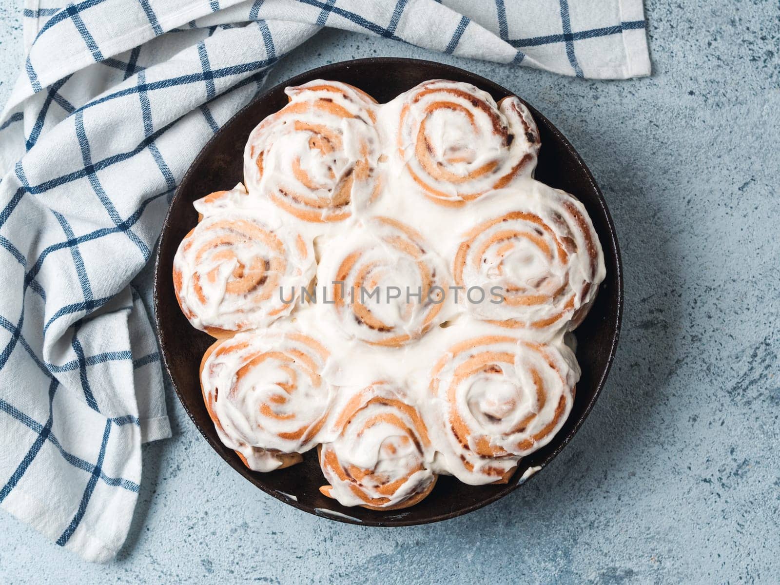 Idea and recipe pastries - perfect cinnamon rolls with topping, top view in skillet. Vegan swedish cinnamon buns Kanelbullar with pumpkin spice,topping vegan cream cheese.Flat lay. Copy space for text