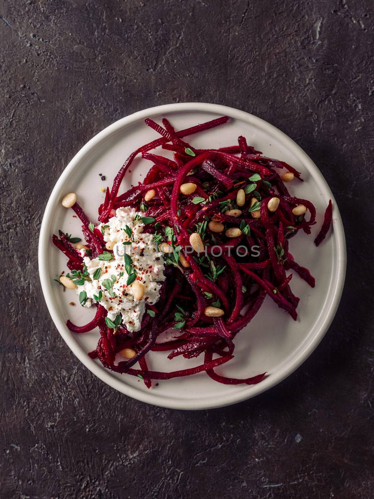 Raw beetroot spaghetti salad with soft cheese,nuts,thyme.Vegetable noodles - Fresh Beetroot Noodles with Ricotta and fresh thyme on plate. Copy space.Clean eating, raw vegetarian food concept.Top view