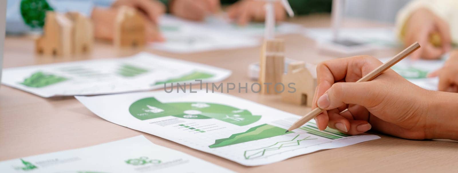 Rising graph representing the profit of using clean energy, displayed on a table at a green business meeting. Environmental documents was scattered around the table. Closeup. Delineation.