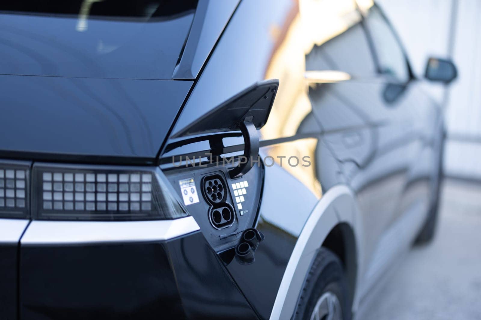 Close-up of CCS Type 2 electric charge plug and socket on black van. Charging port on a modern electric car. Fast charging socket type 2 combo electric car. Type 2 CCS plug port on electric vehicle by uflypro