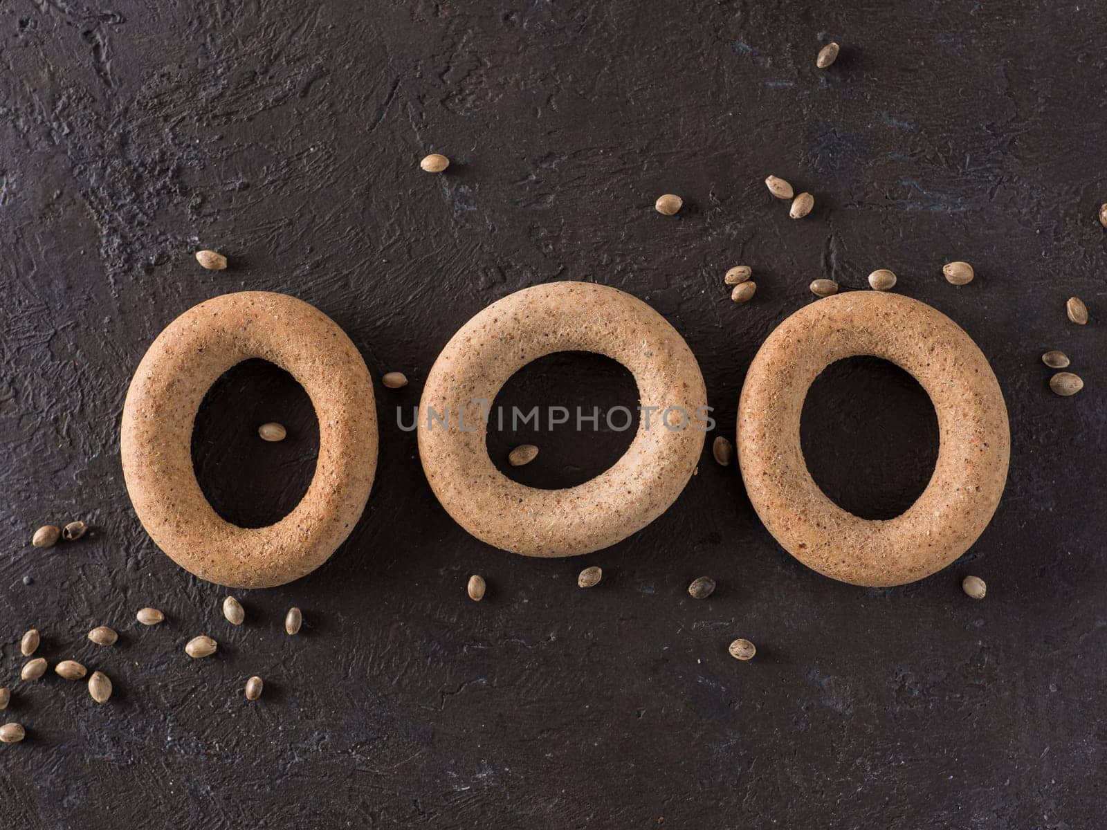 Ring-shaped cracknel with whole grain hemp seed flour and hemp seeds on black background. ring-shaped cracknel close up. Copy space Top view or flat lay.