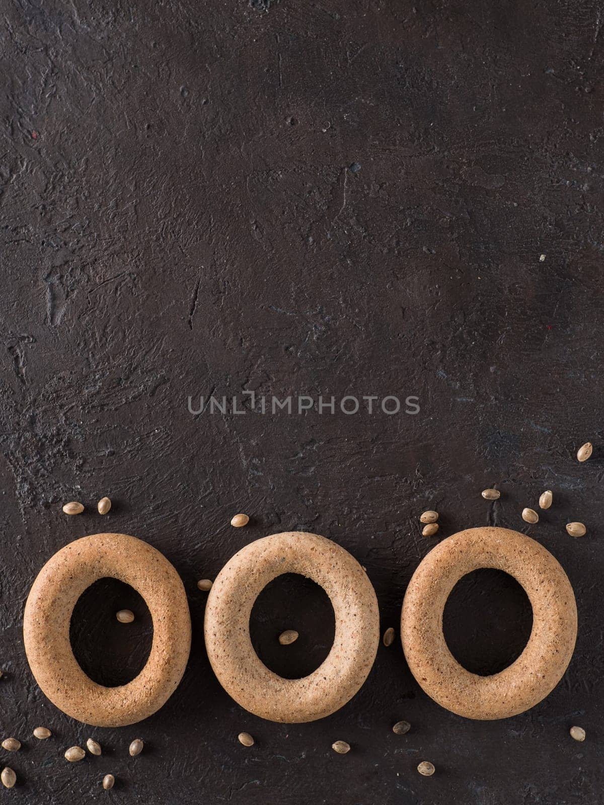 Ring-shaped cracknel with whole grain hemp seed flour and hemp seeds on black background. ring-shaped cracknel close up. Copy space Top view or flat lay. Vertical.