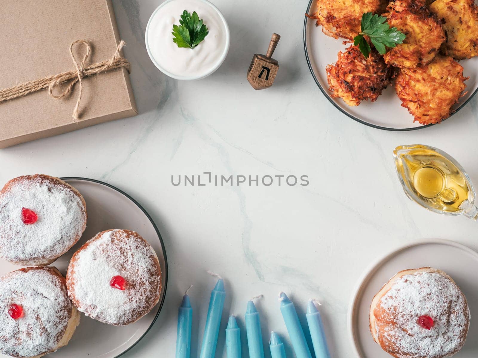 Jewish holiday Hanukkah concept and background. Hanukkah food doughnuts and potatoes pancakes latkes, oil, candles, gift box and traditional spinnig dreidl. Top view or flat lay. Copy space for text