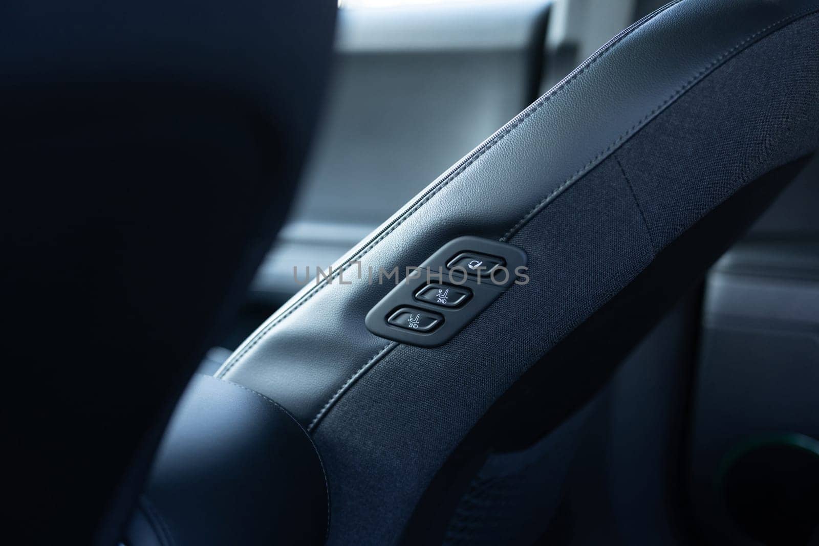 Rear seat passenger switch to control the front passenger seat. Walk-in seat switch. Luxury car interior. Electric car seat position adjustment buttons.